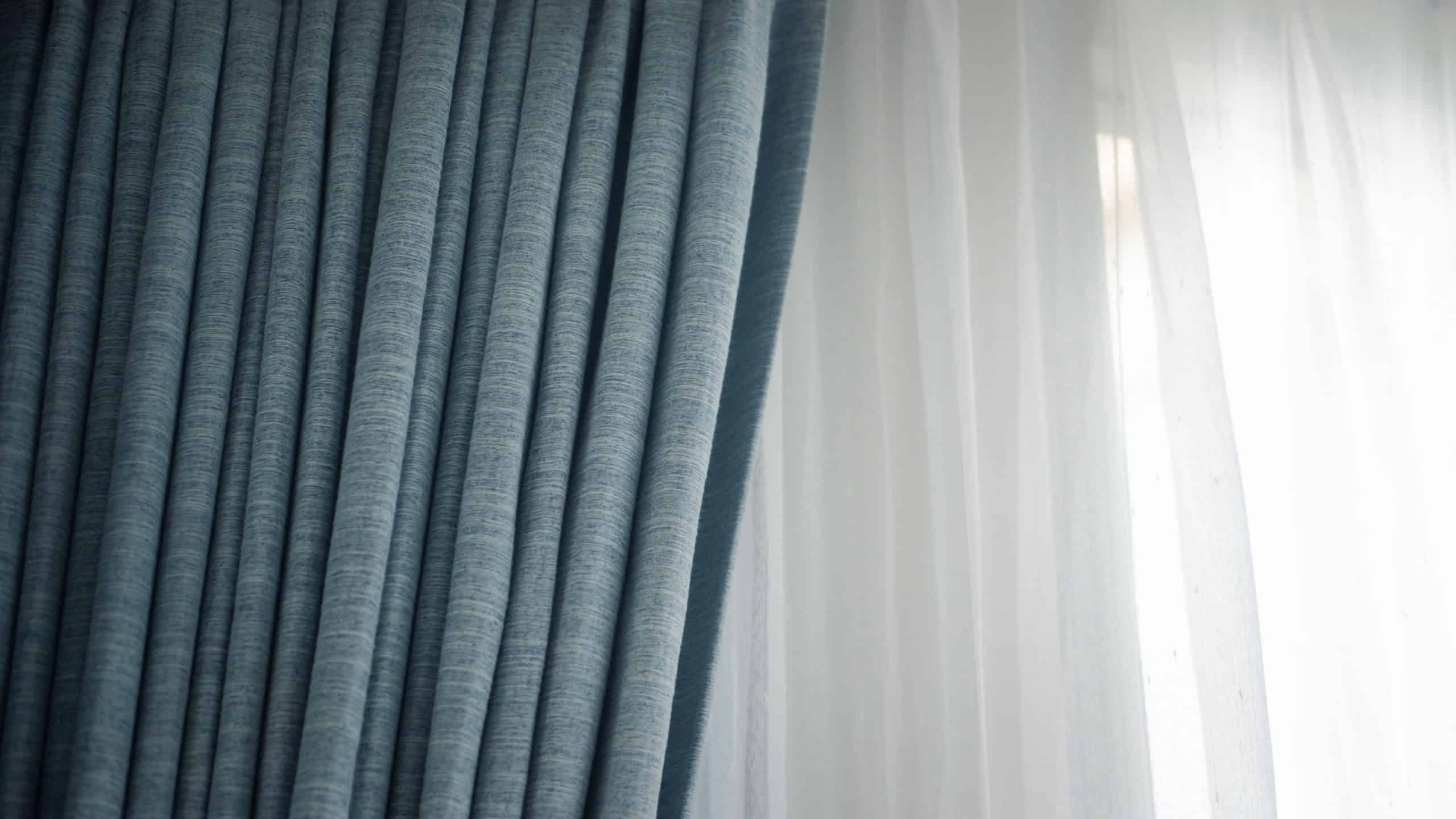 Light coming through a sheer, transparent and pleated light curtains or drapes. Window with drapes covering it