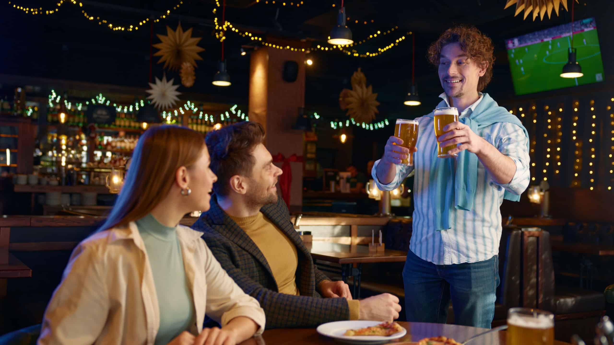 Cheerful guy buying friends beer during rest in bar