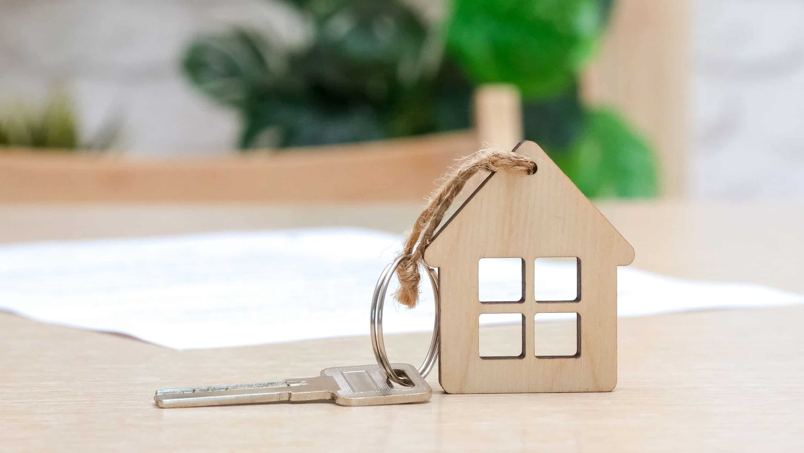 Key with house shaped keychain and contract on the table. Mortgage, home loan and insurance, buying house, real estate concept. Selective focus