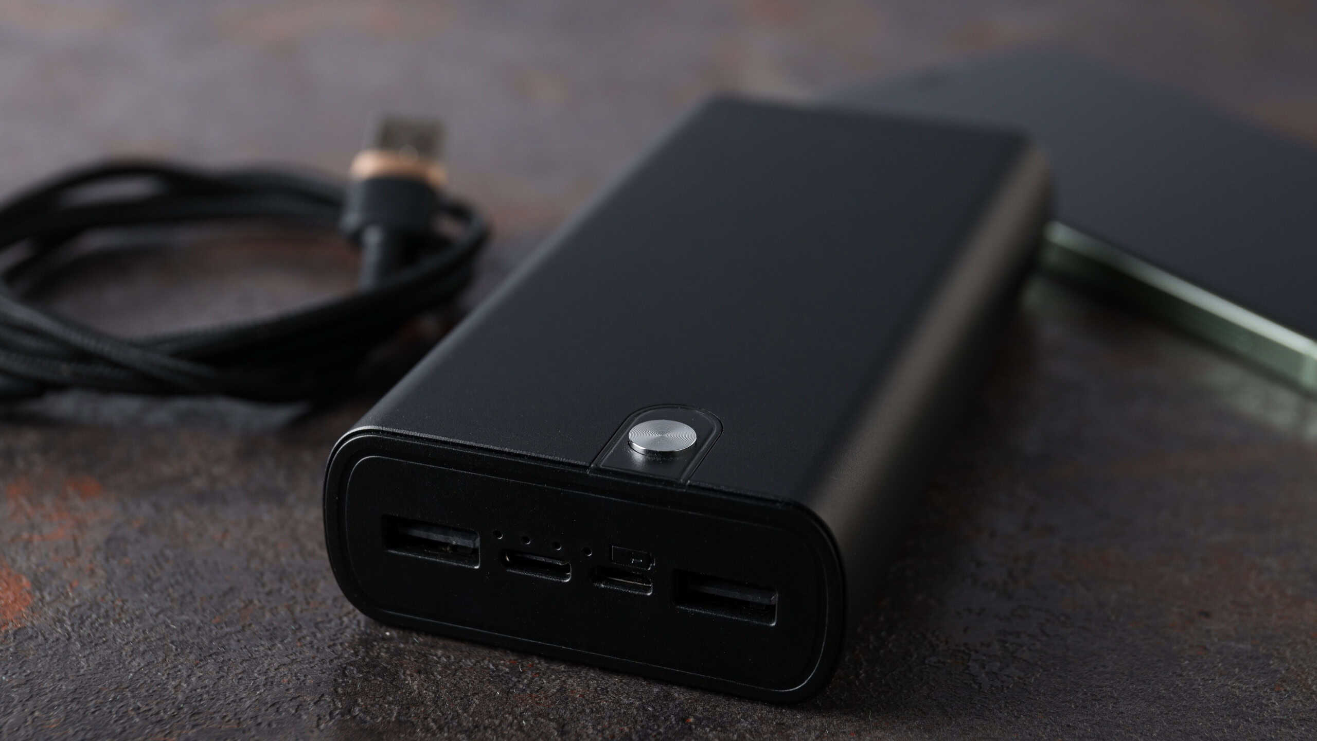 Powerbank, cord and smartphone on gray background, close up
