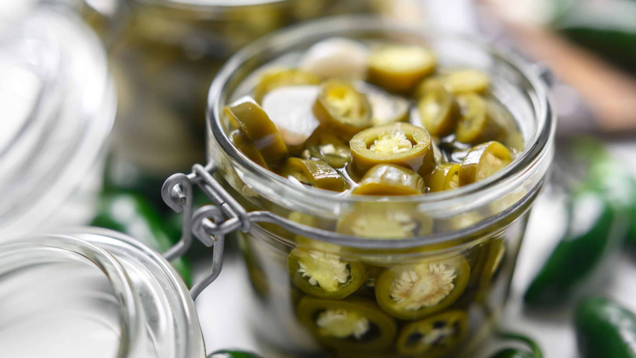 Pickled green mexican jalapeno hot peppers in a mason jar close up. Food photography