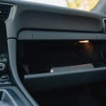 Minimalist glove box design with smooth, black interior finish in a luxury vehicle.