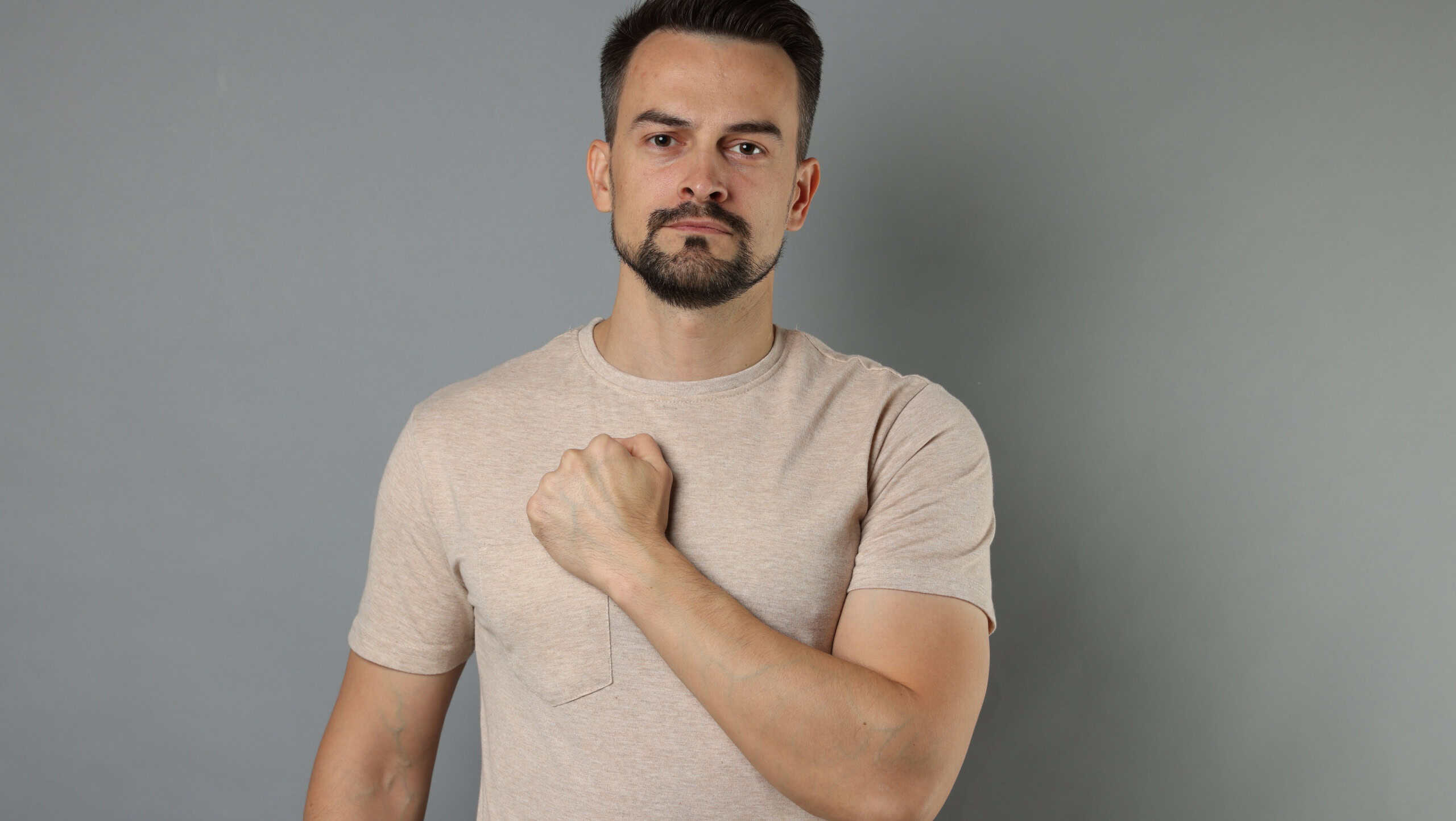 Man making promise on grey background. Oath gesture