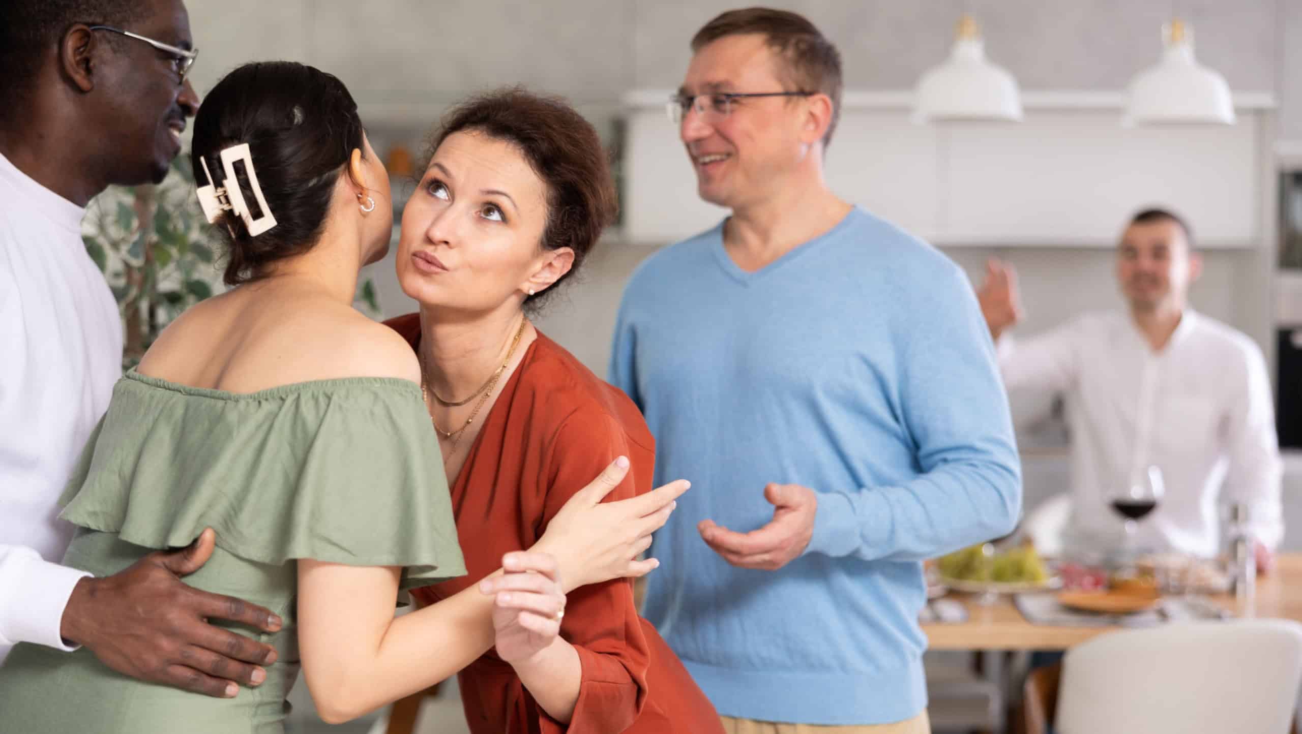 Multicultural female and male friends greeting each other when meeting in kitchen