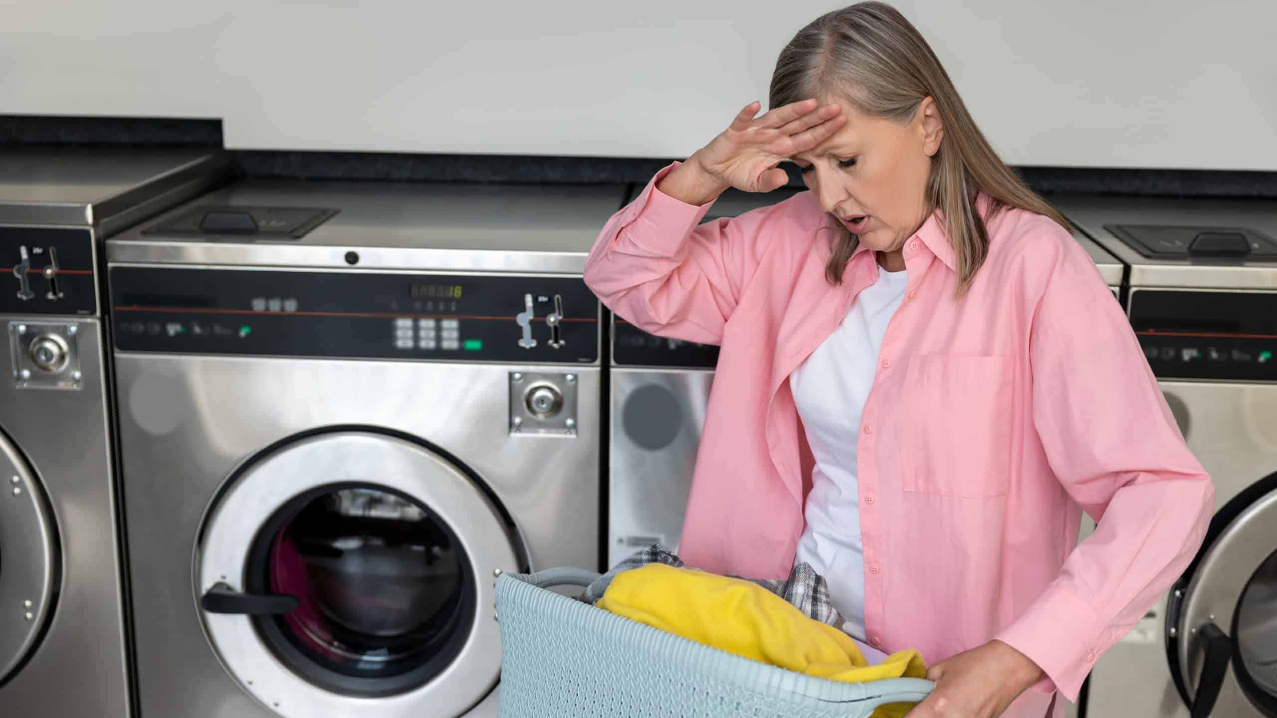 Mature caucasian woman in pink tshirt looking tired while doing housework