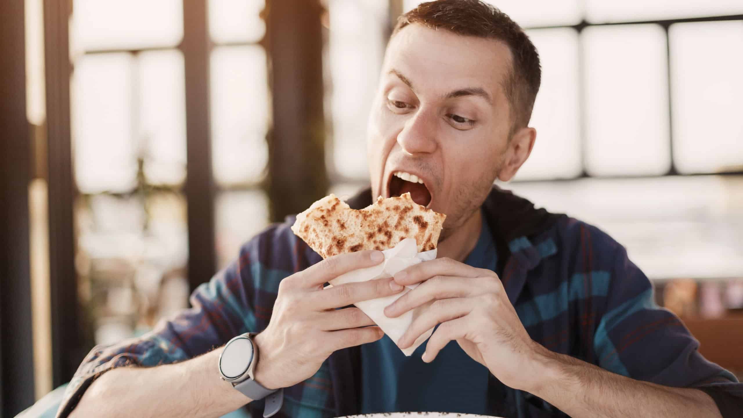 Young man savoring a delicious sweet crepe while seated at a restaurant table, enjoying the flavors of casual dining during lunchtime