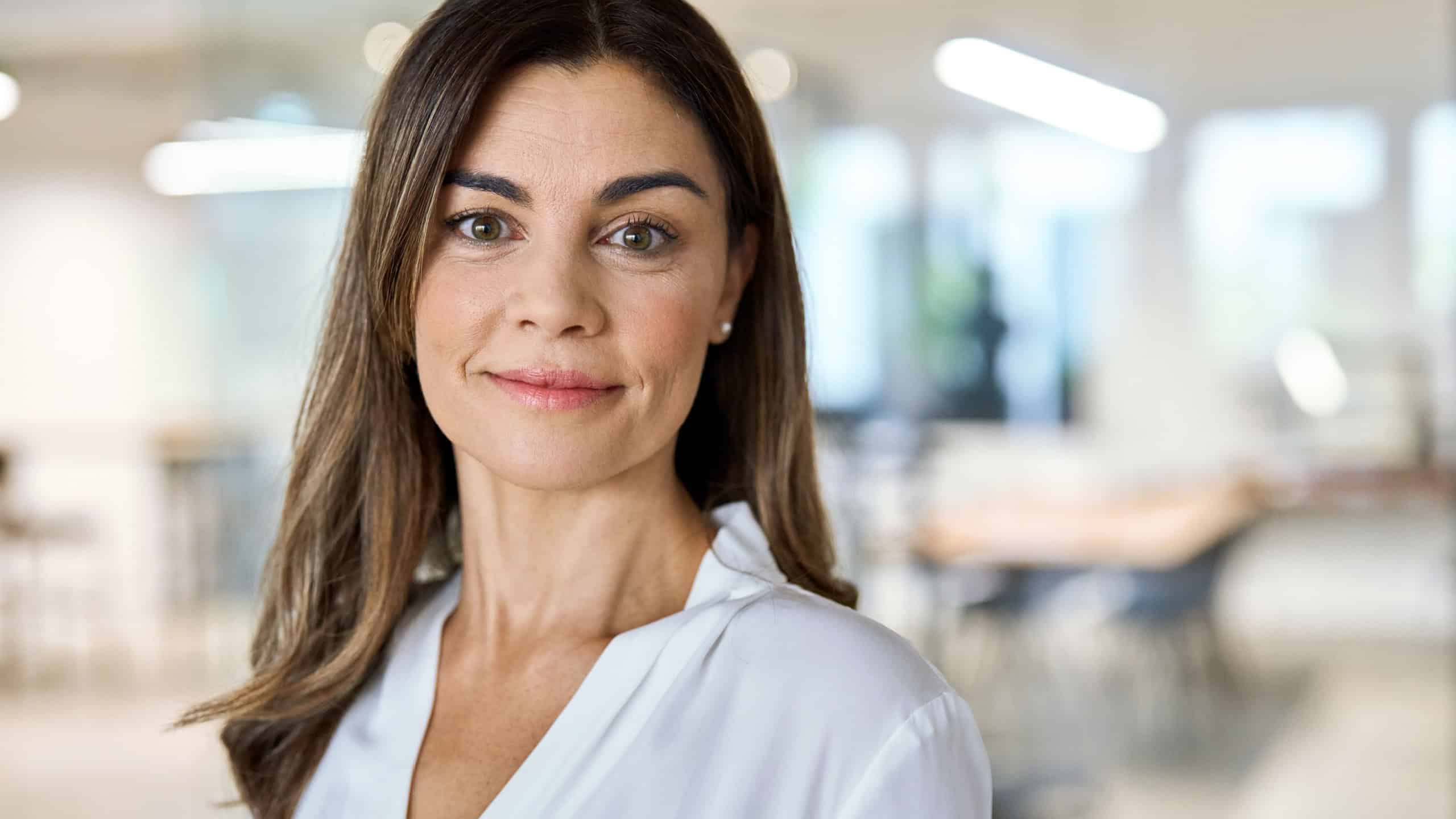 Headshot portrait of happy middle aged business woman, smiling 45 years old businesswoman, mature female professional executive manager leader standing in corporate office looking at camera.