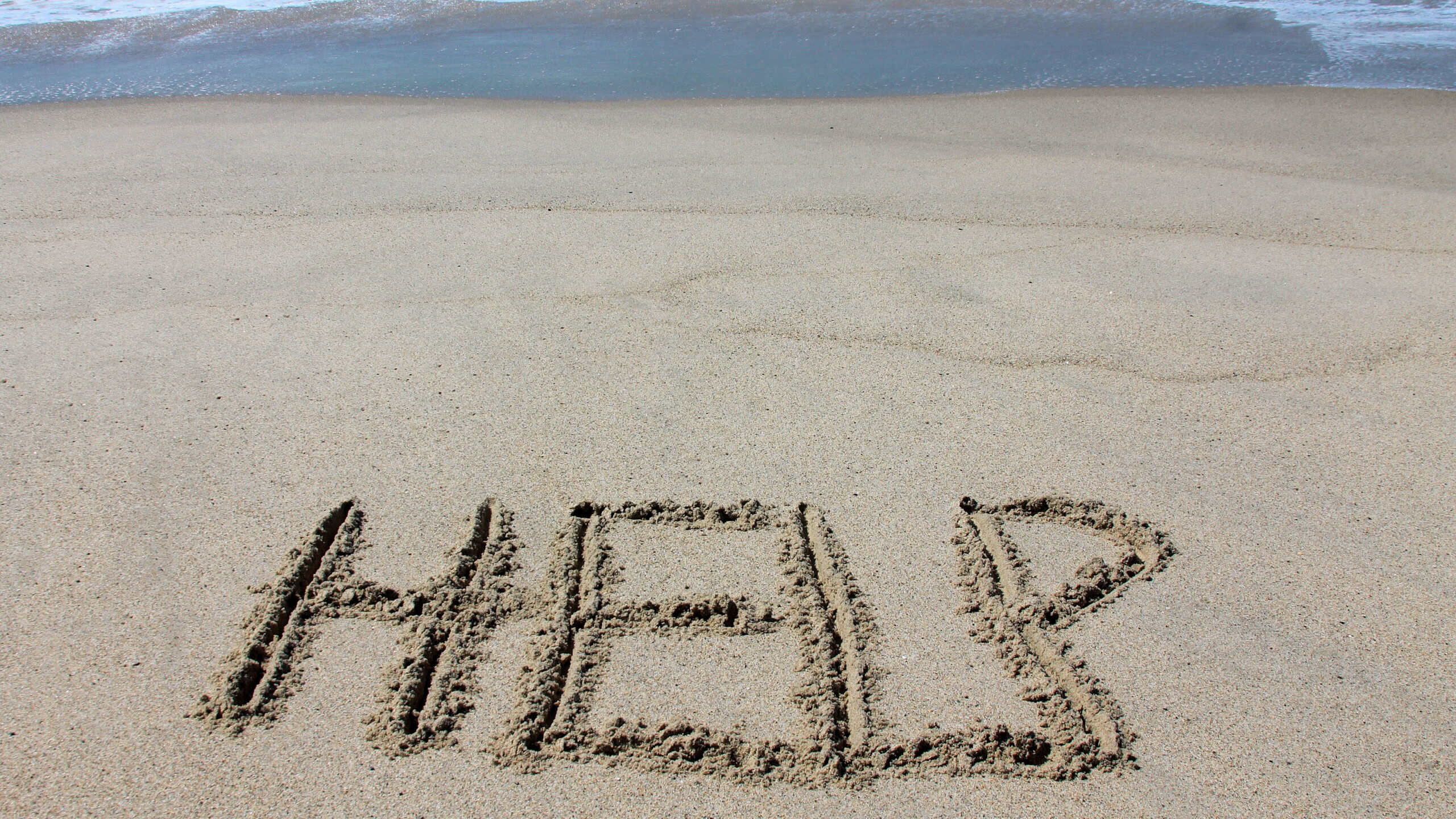 HELP. The word HELP written in the sand on the beach. Messages written in the sand on the beach. The word HELP written in the sand. Pacific Ocean. Laguna Beach, California. S.O.S. Lost and Found.