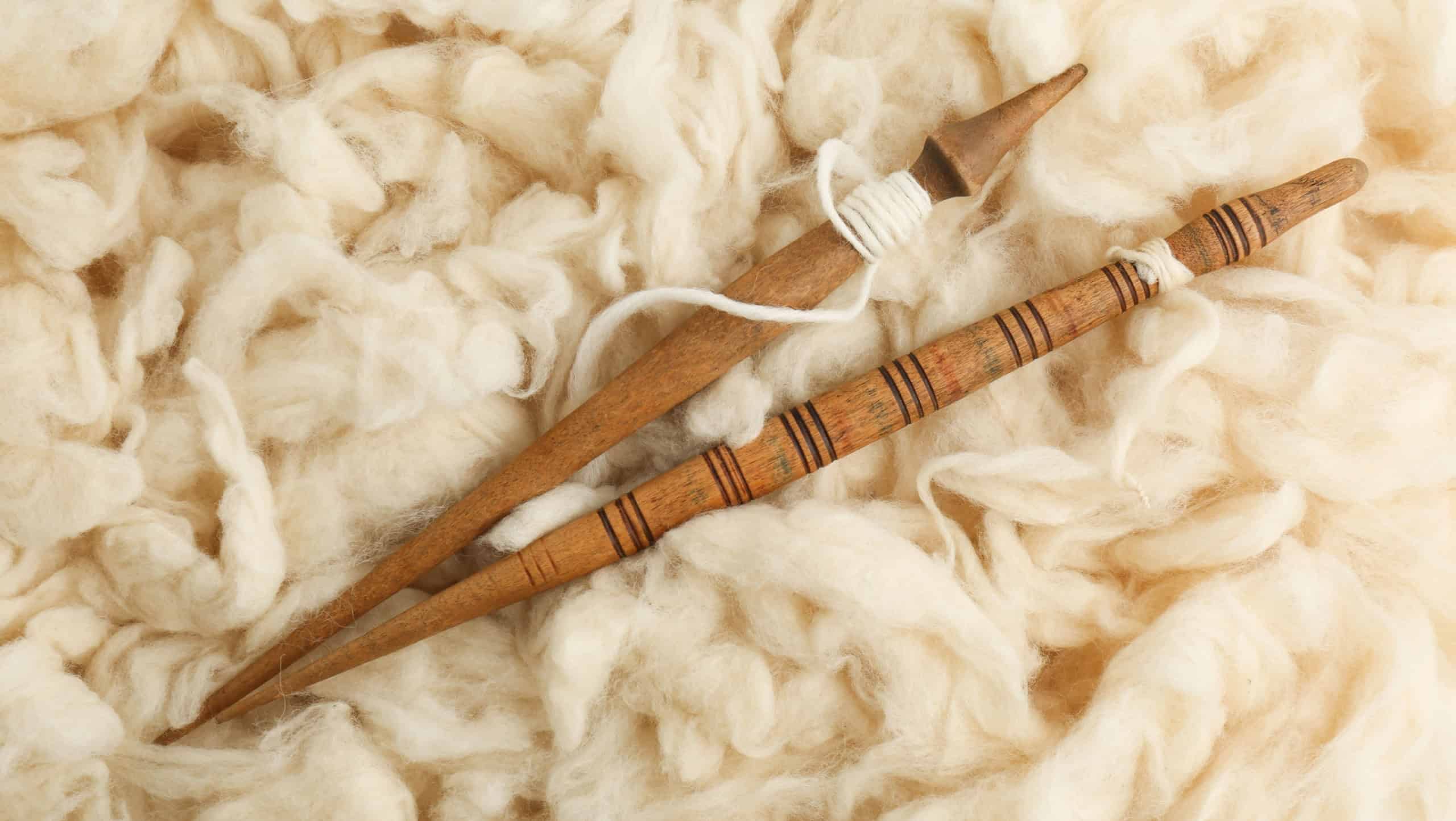 Soft white wool with spindles as background, top view