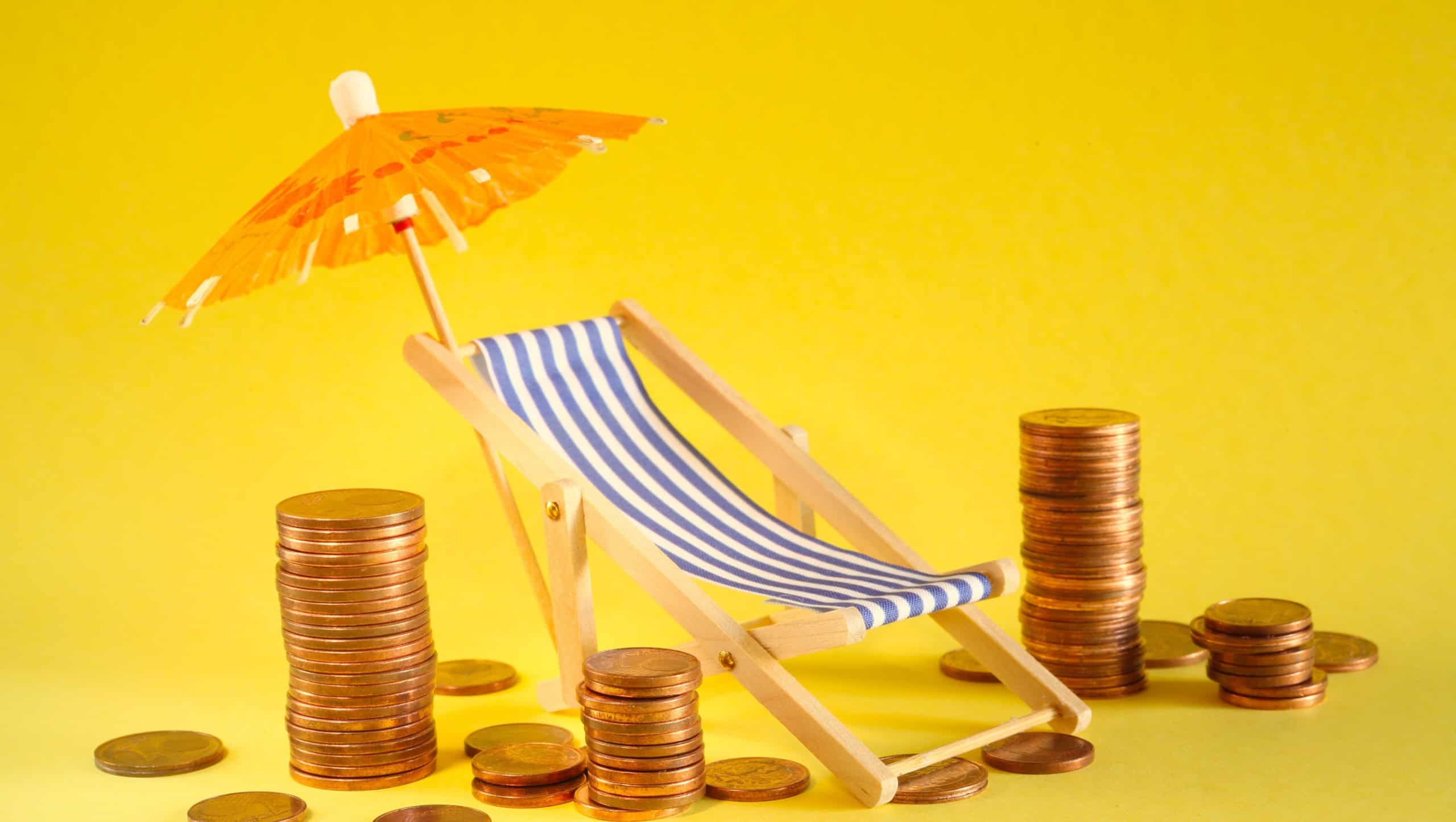 rising prices for vacation and summer holidays or wealth management concept,heap of coins, sun umbrella and deck chair, free copy space. Close up shot with narrow depth of field.