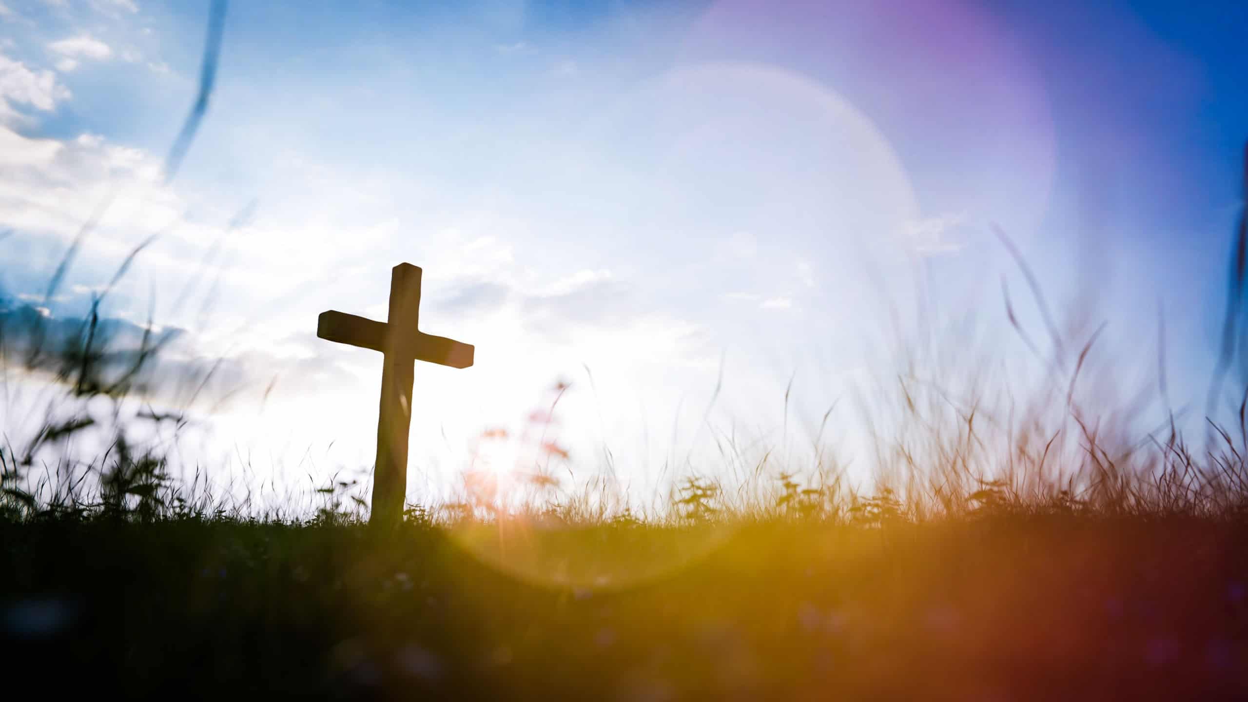 Wooden cross standing on a hill at sunset, symbolizing christian faith, spirituality, and resurrection