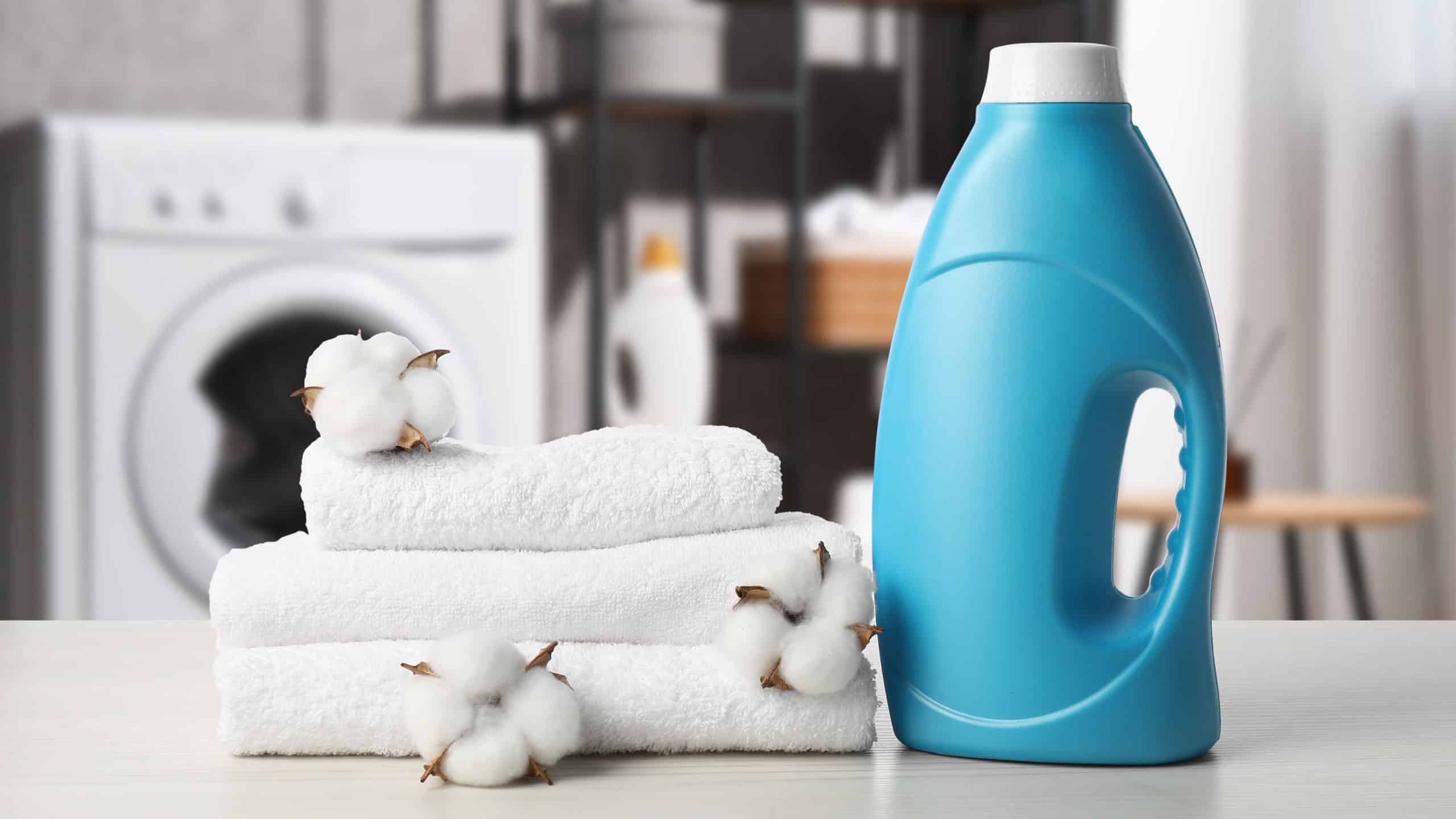 Fabric softener, towels and cotton flowers on table in laundry room