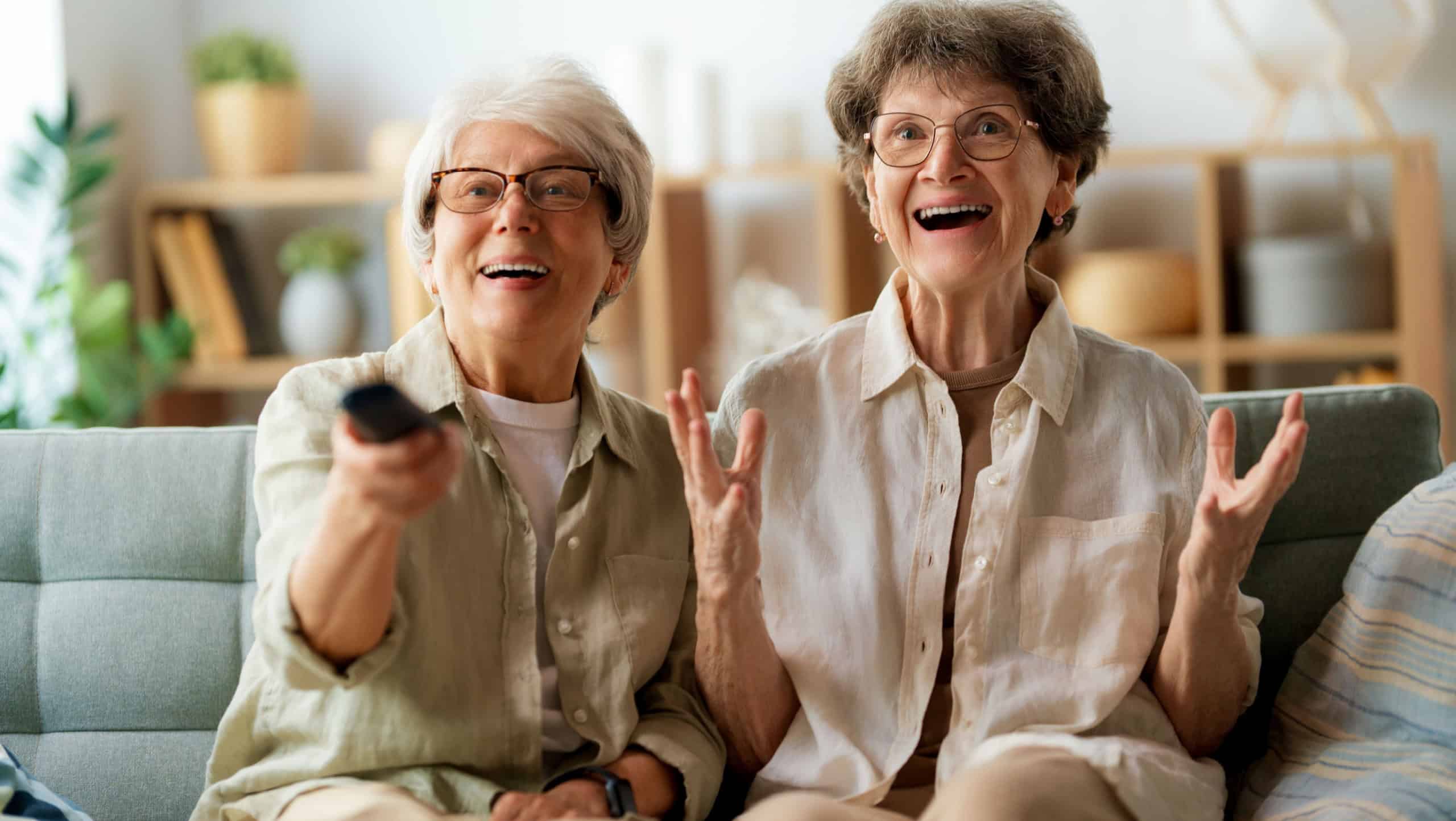 Senior women watching TV, movies. Retirees spending time at home.