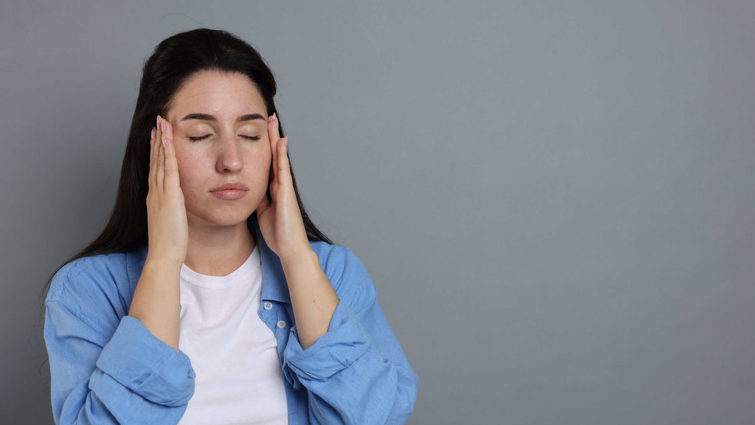 Panic attack. Woman calming herself down on grey background, space for text
