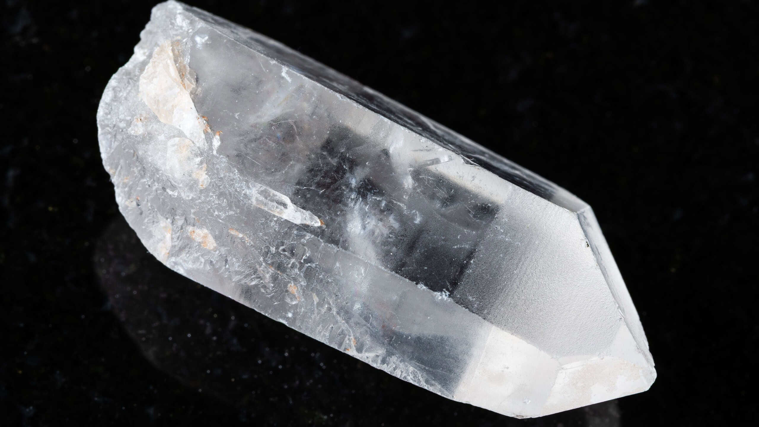 Sample of raw rock crystal on black granite background close up