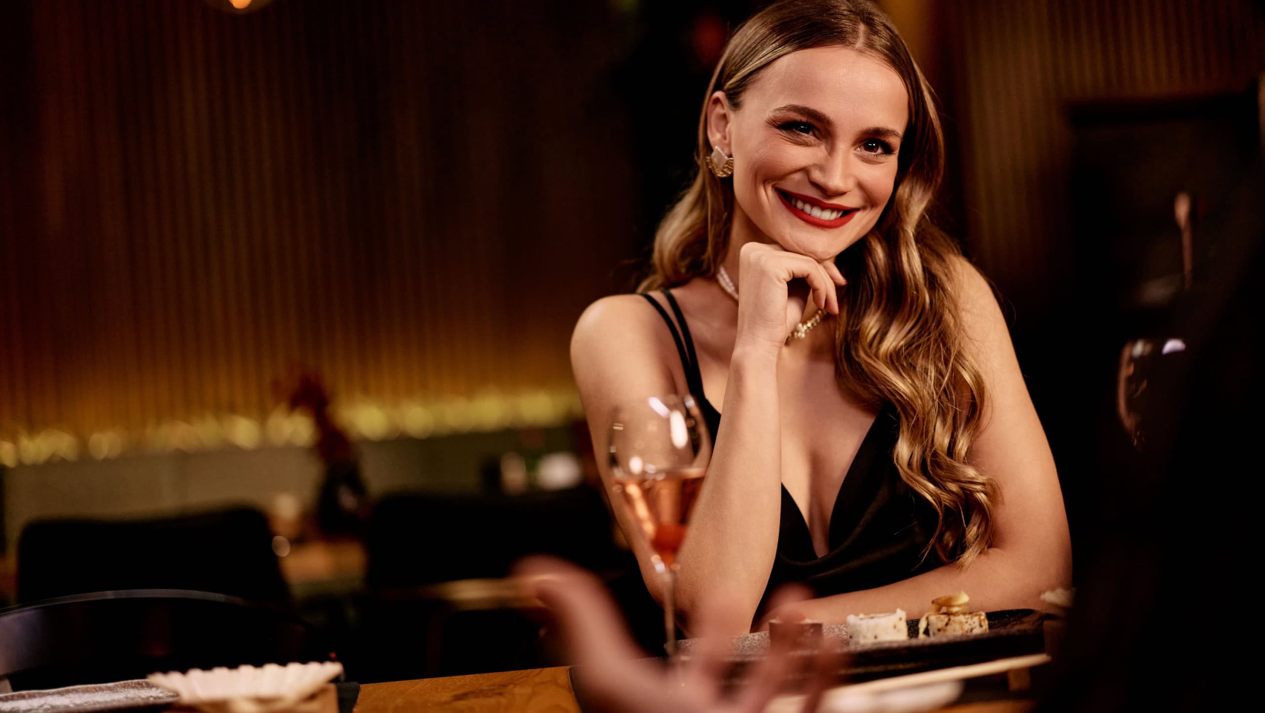 Woman smiles during a dinner date at a sophisticated restaurant.