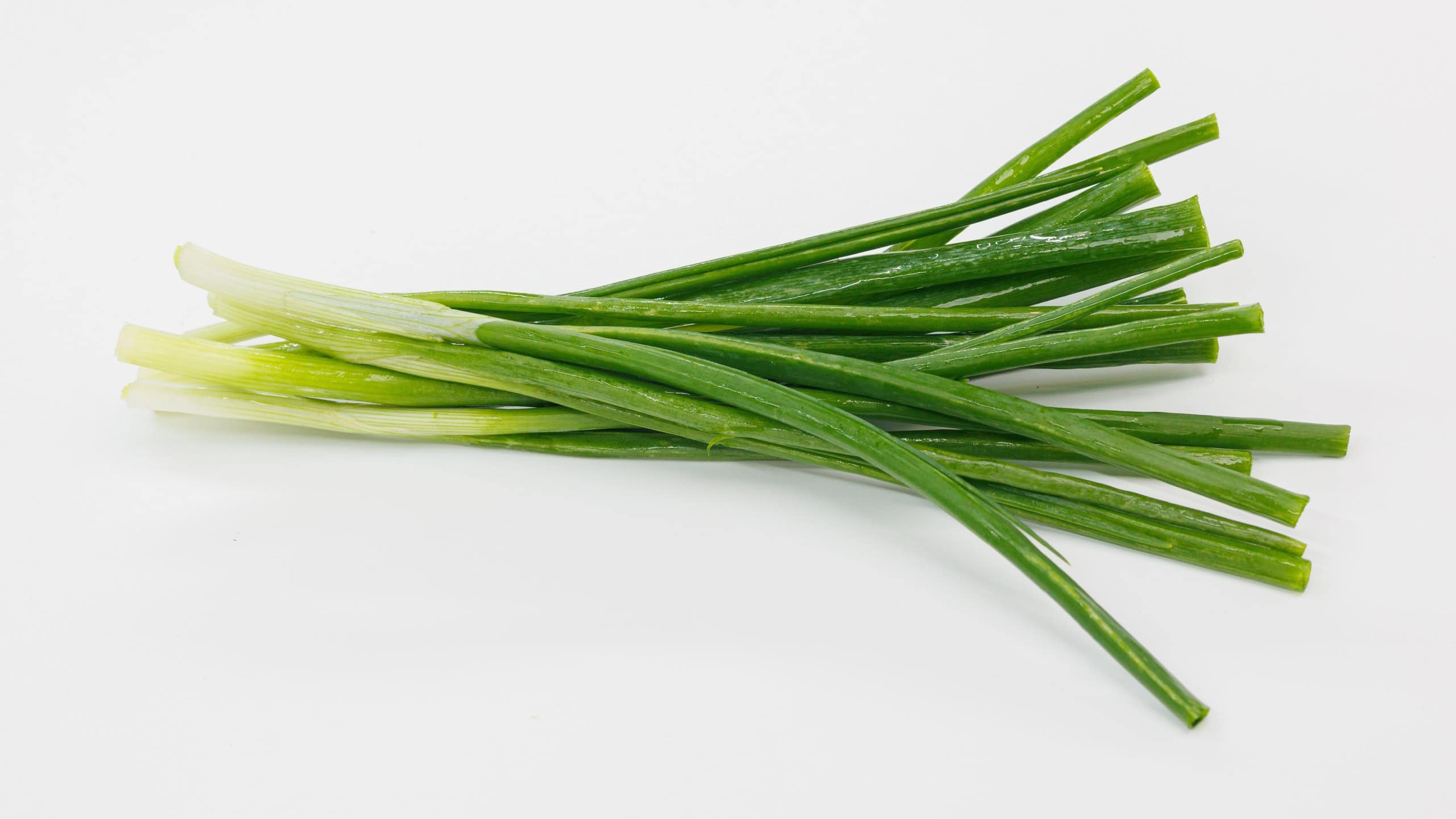 A bright bundle of green onions laid on a clean white background. Perfect for cooking, garnishes, salads, or healthy meal ideas and recipe visuals.