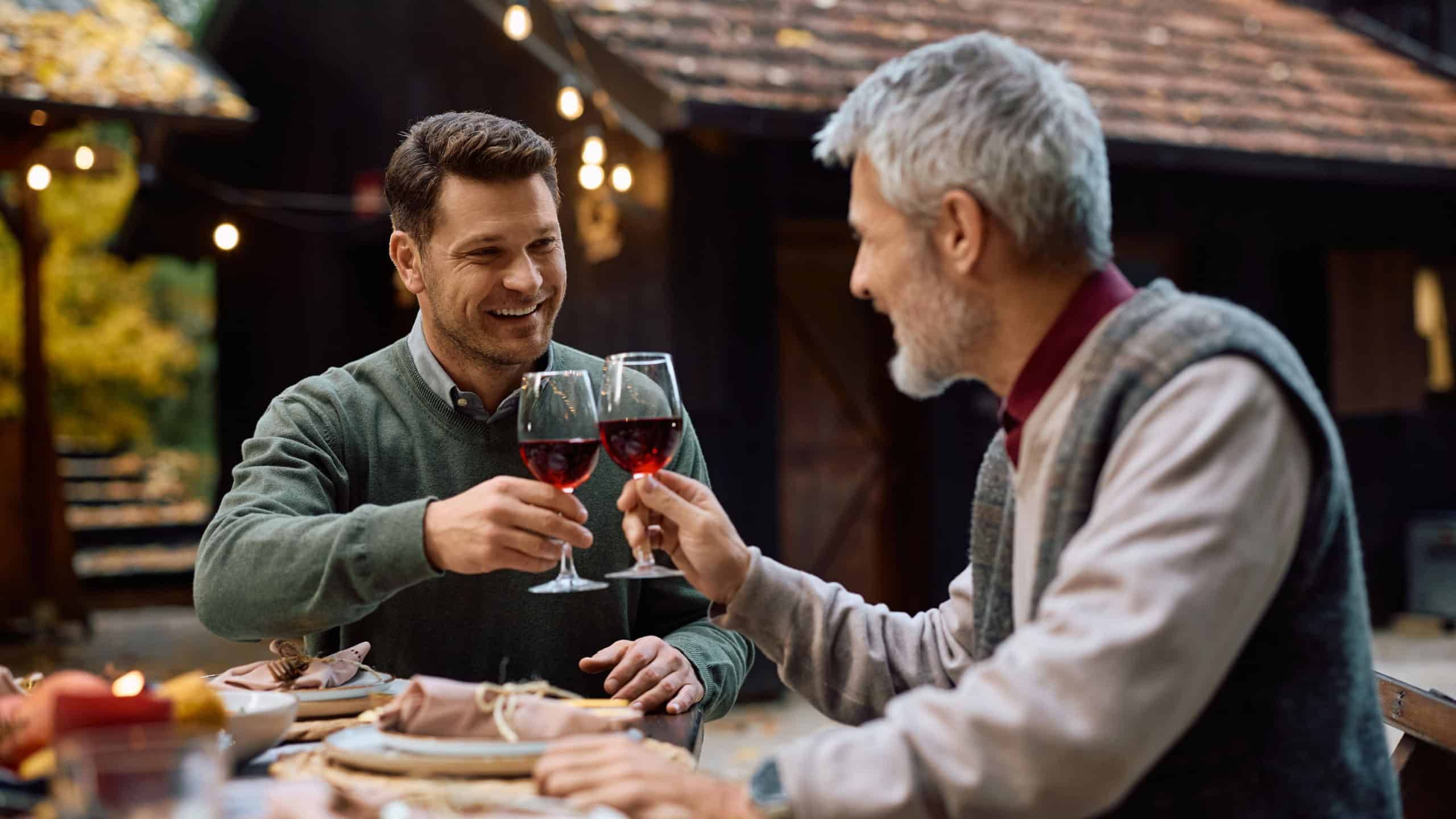 Happy man toasting with his mature father while celebrating Thanksgiving together.