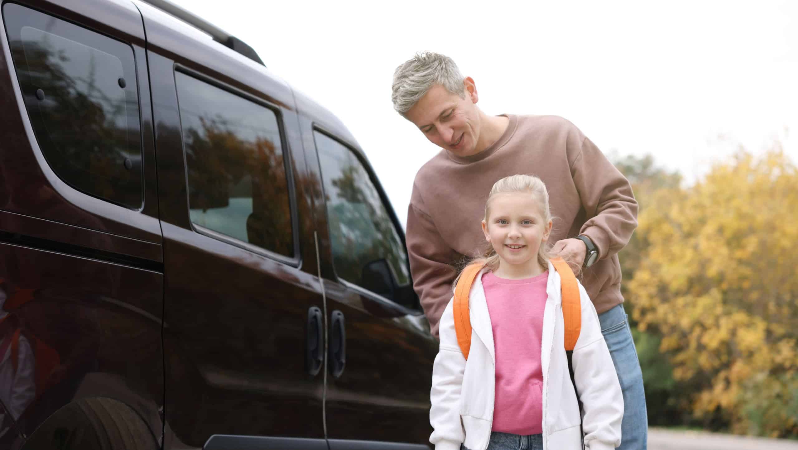 Father taking his daughter to school near car outdoors