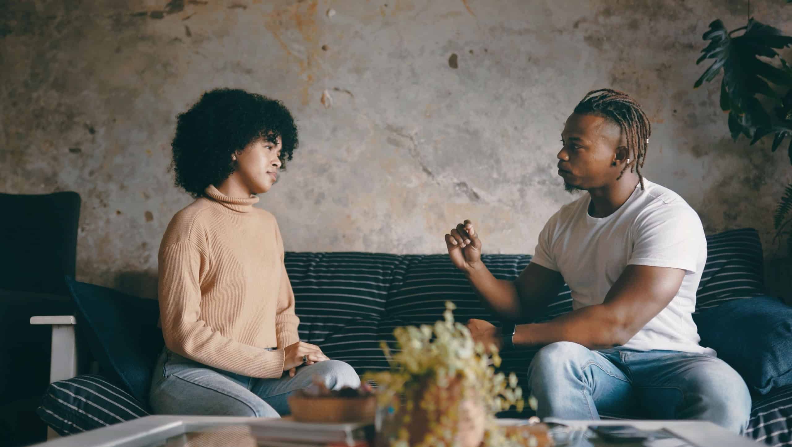 Home, talking and black couple on sofa, disagreement and marriage with toxic relationship. Serious, man and woman on couch, conversation or listening with cheating, divorce or unhappy with breakup