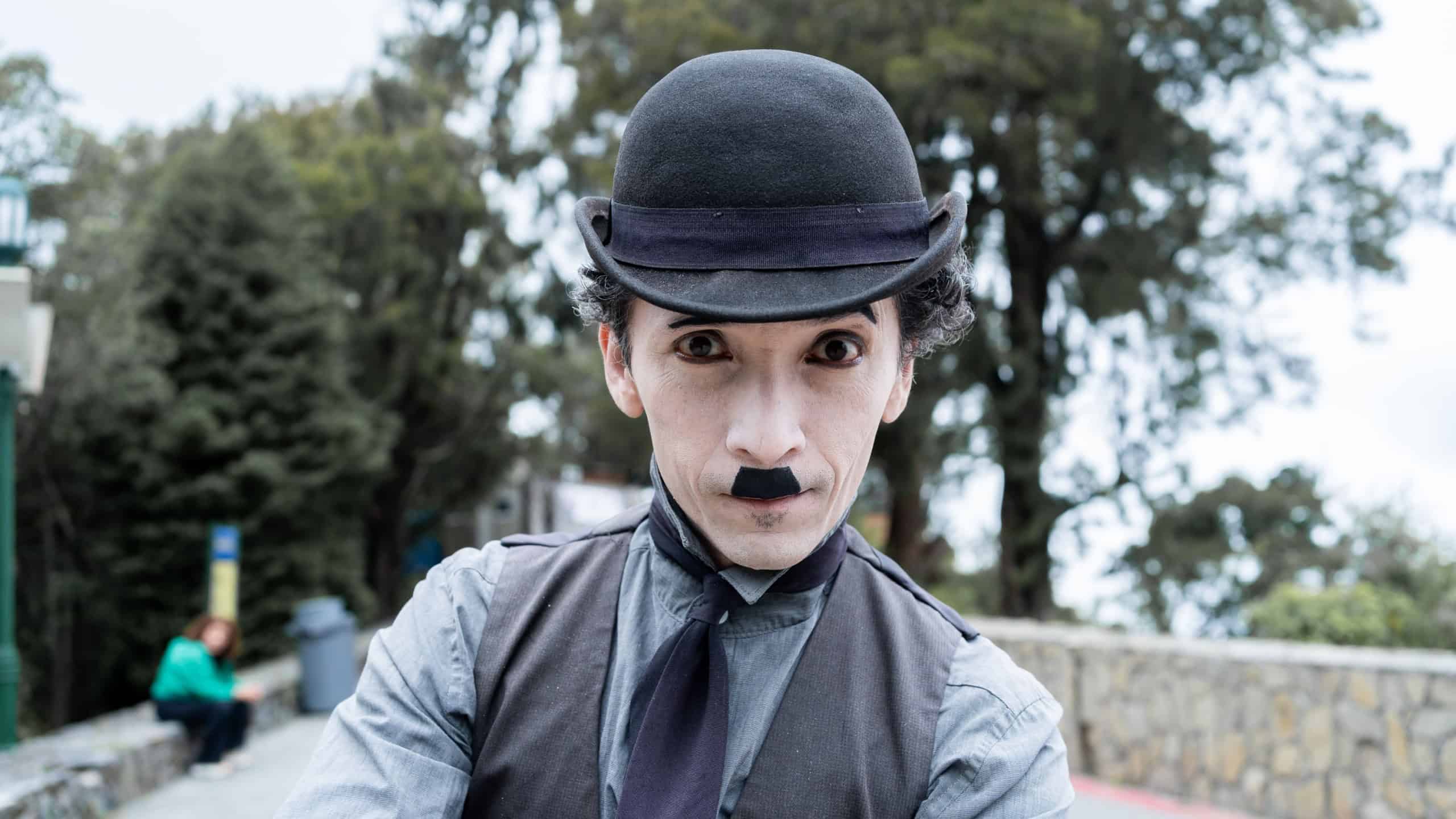 Young Charlie Chaplin impersonator stares intently in a manner similar to the artist.