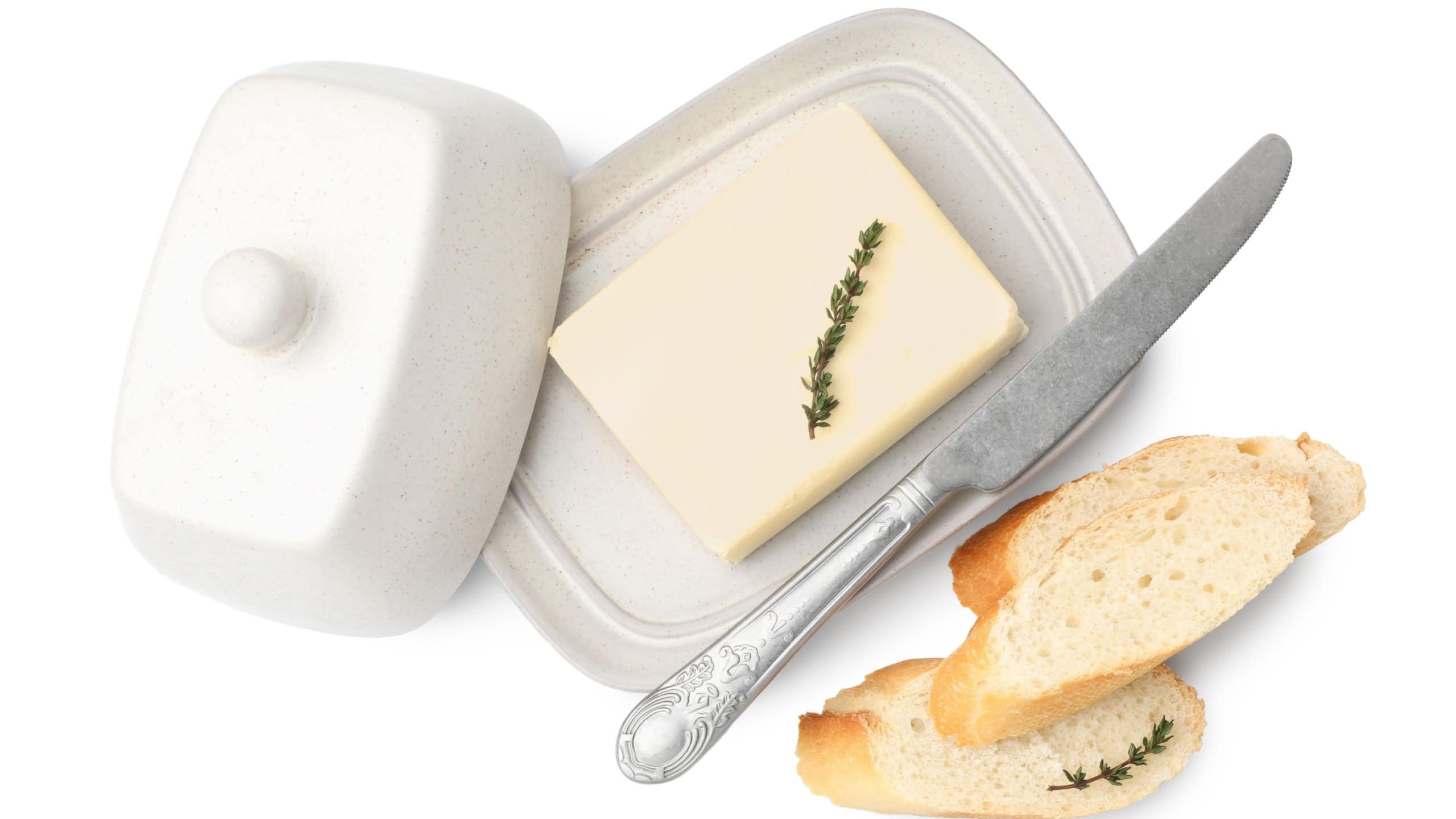 Slices of baguette with butter, thyme and knife isolated on white, top view