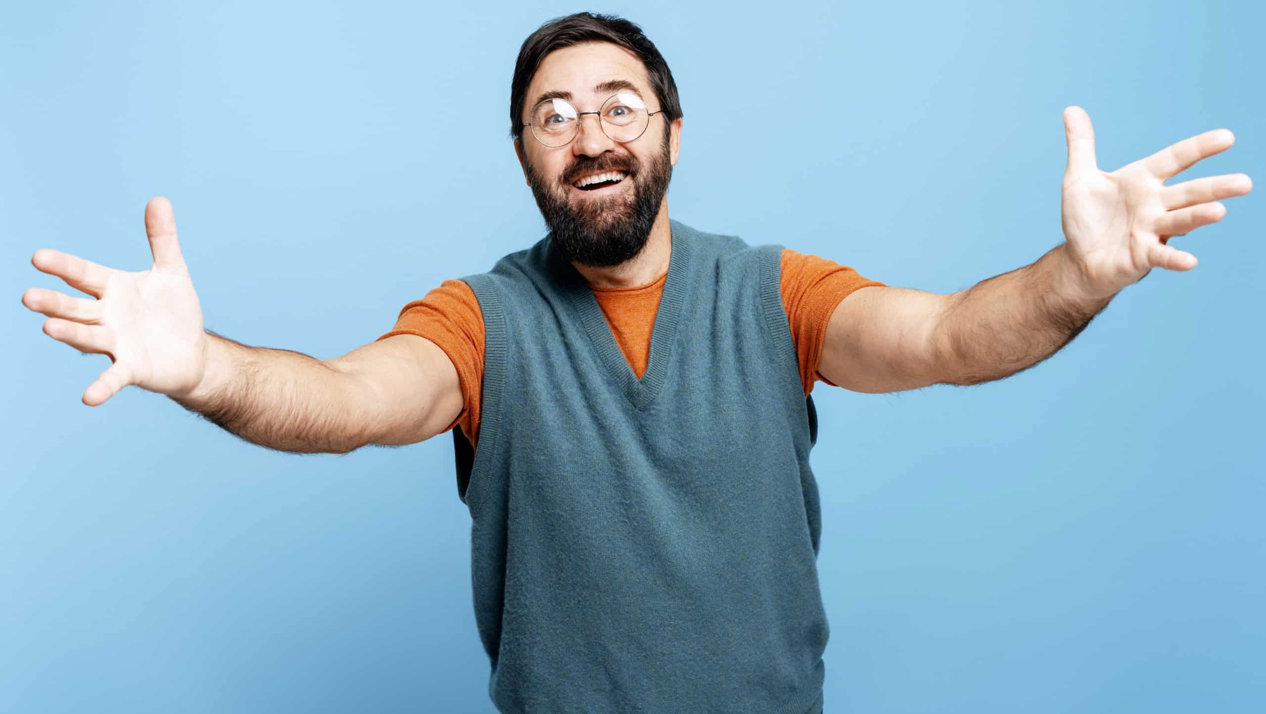 Cheerful man welcoming with open arms, expressing happiness and readiness for a hug