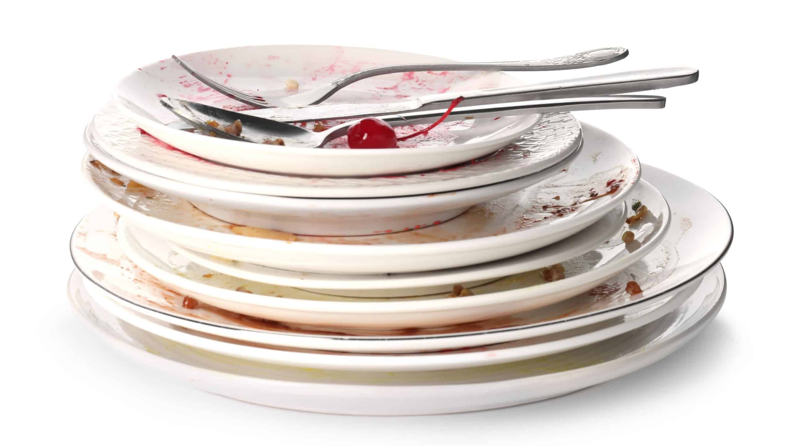 Stack of dirty plates and cutlery isolated on white