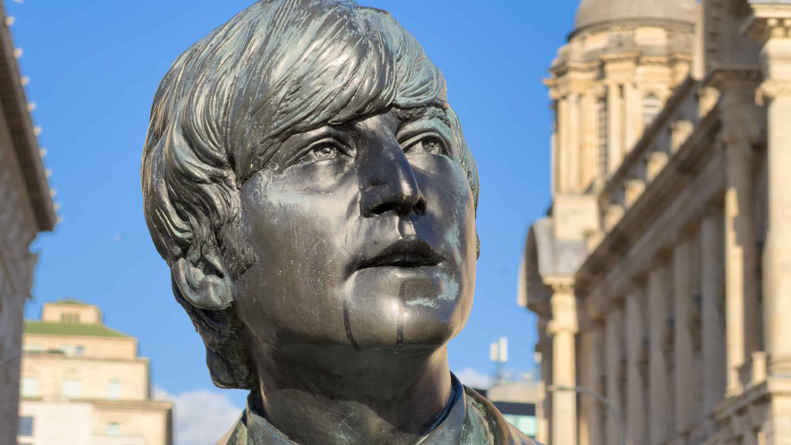 A detailed close-up view of the bronze statue of John Lennon, part of The Beatles statue group located at Pier Head in Liverpool