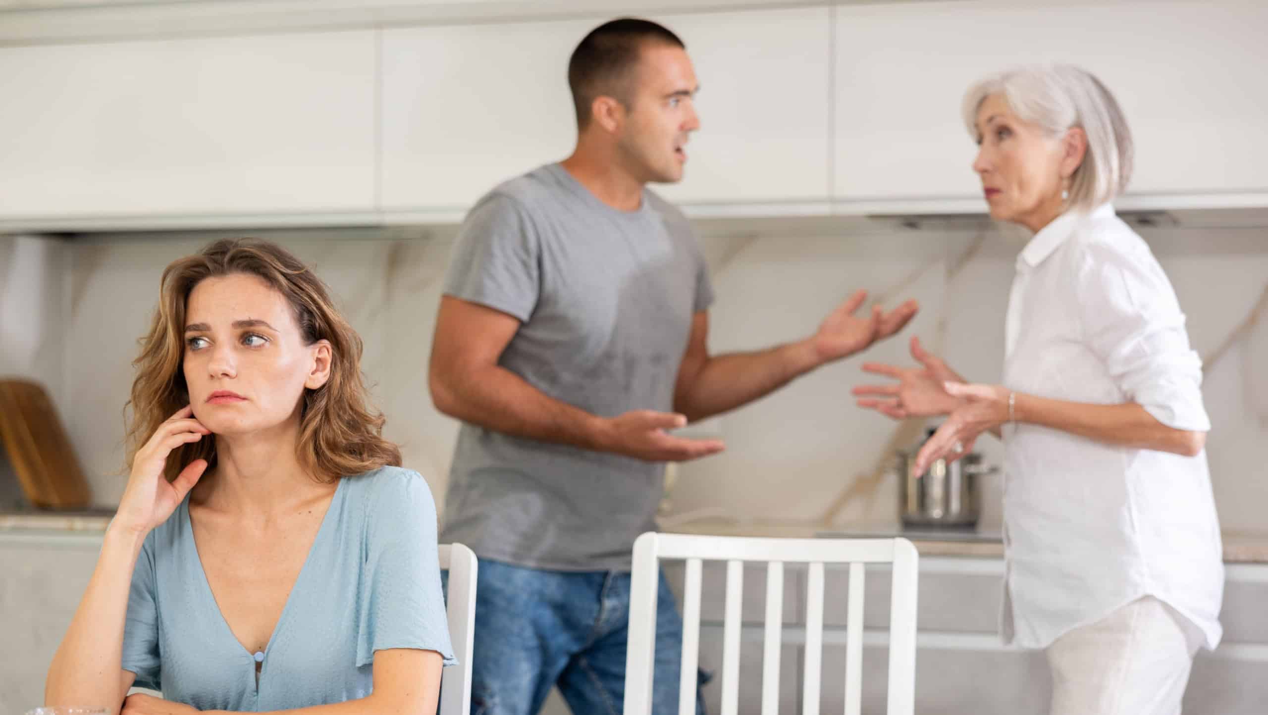 Elderly woman gets angry during quarrel with man and woman couple in kitchen