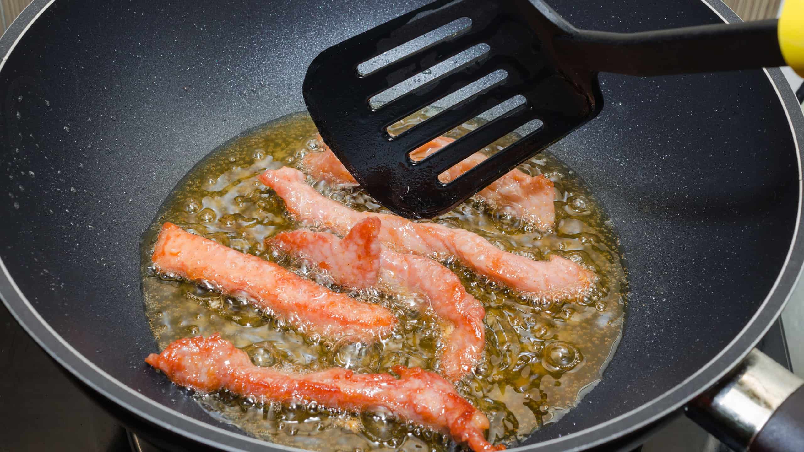 Meat Strips Fried In A Black Pan, In boiling oil