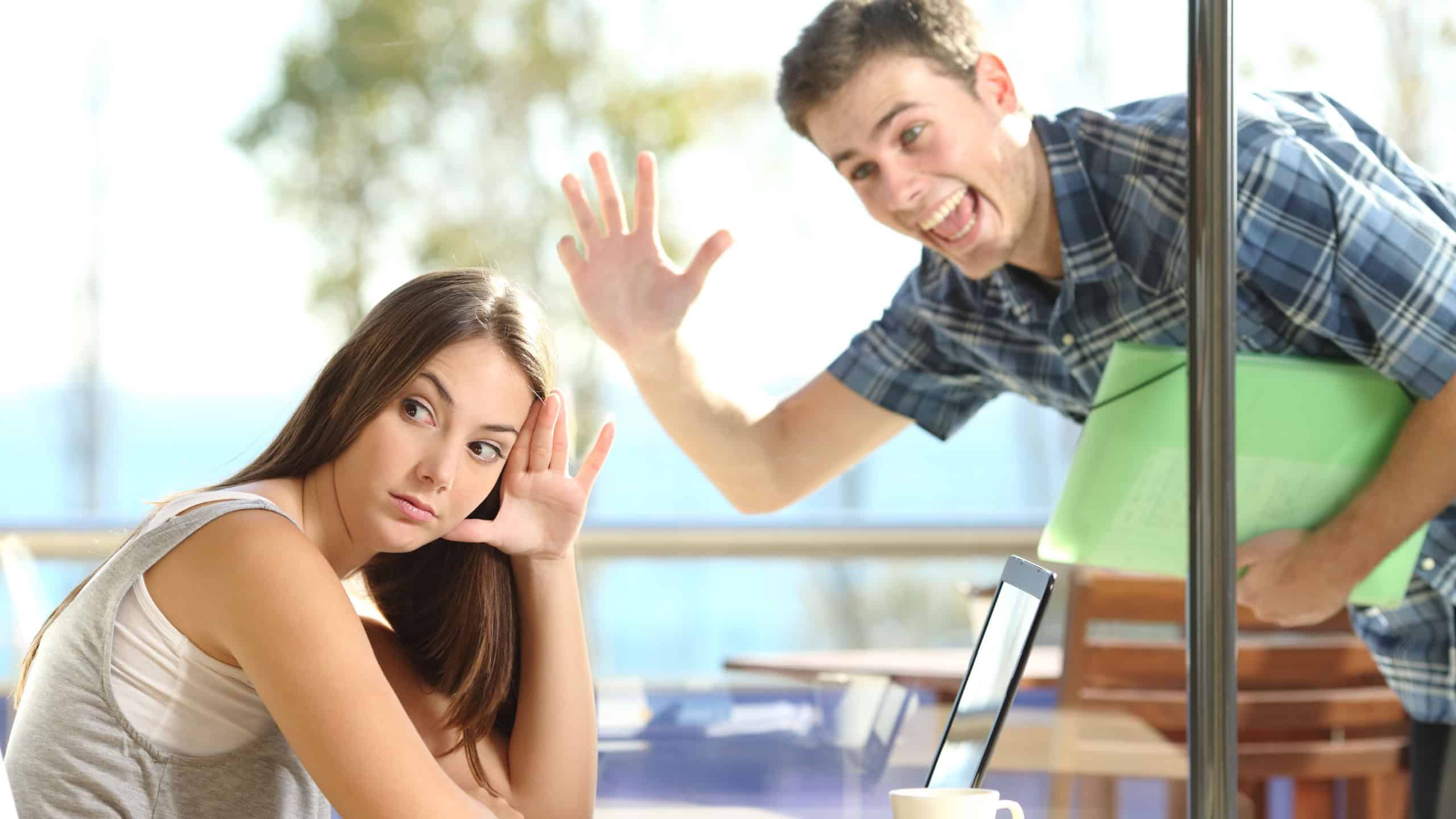Girl ignoring and rejecting to a stalker man waving her in a coffee shop in a blind date