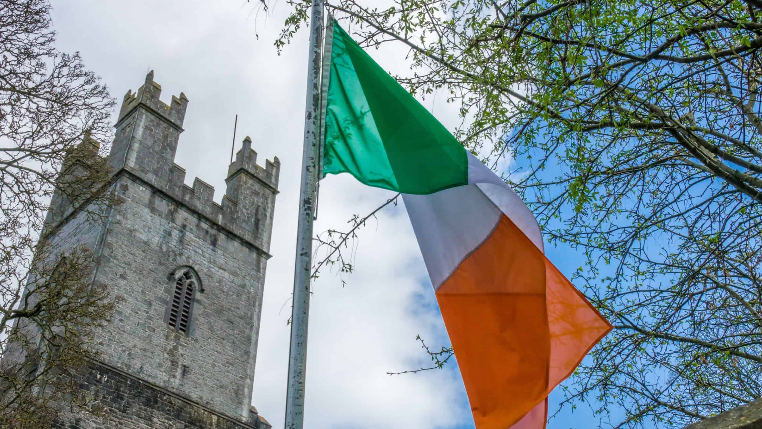 Irish flag fluttering in front of the tower of an Old St Mary Cathedral, Limerick, Ireland
