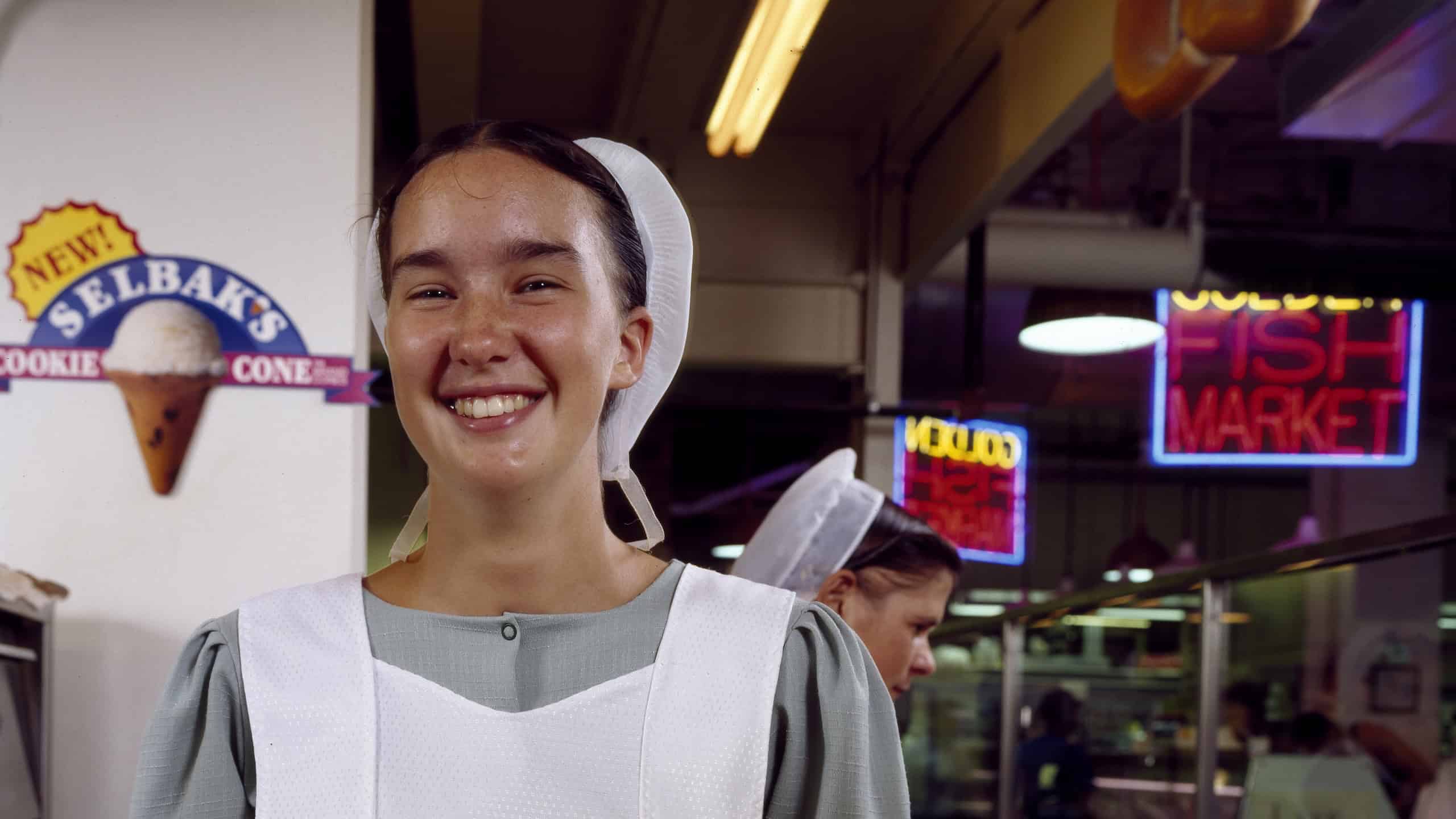 At the Reading Terminal Market, a young Amish woman from Lancaster County serves fresh-cooked soft pretzels, a time-honored Philadelphia delicacy.
