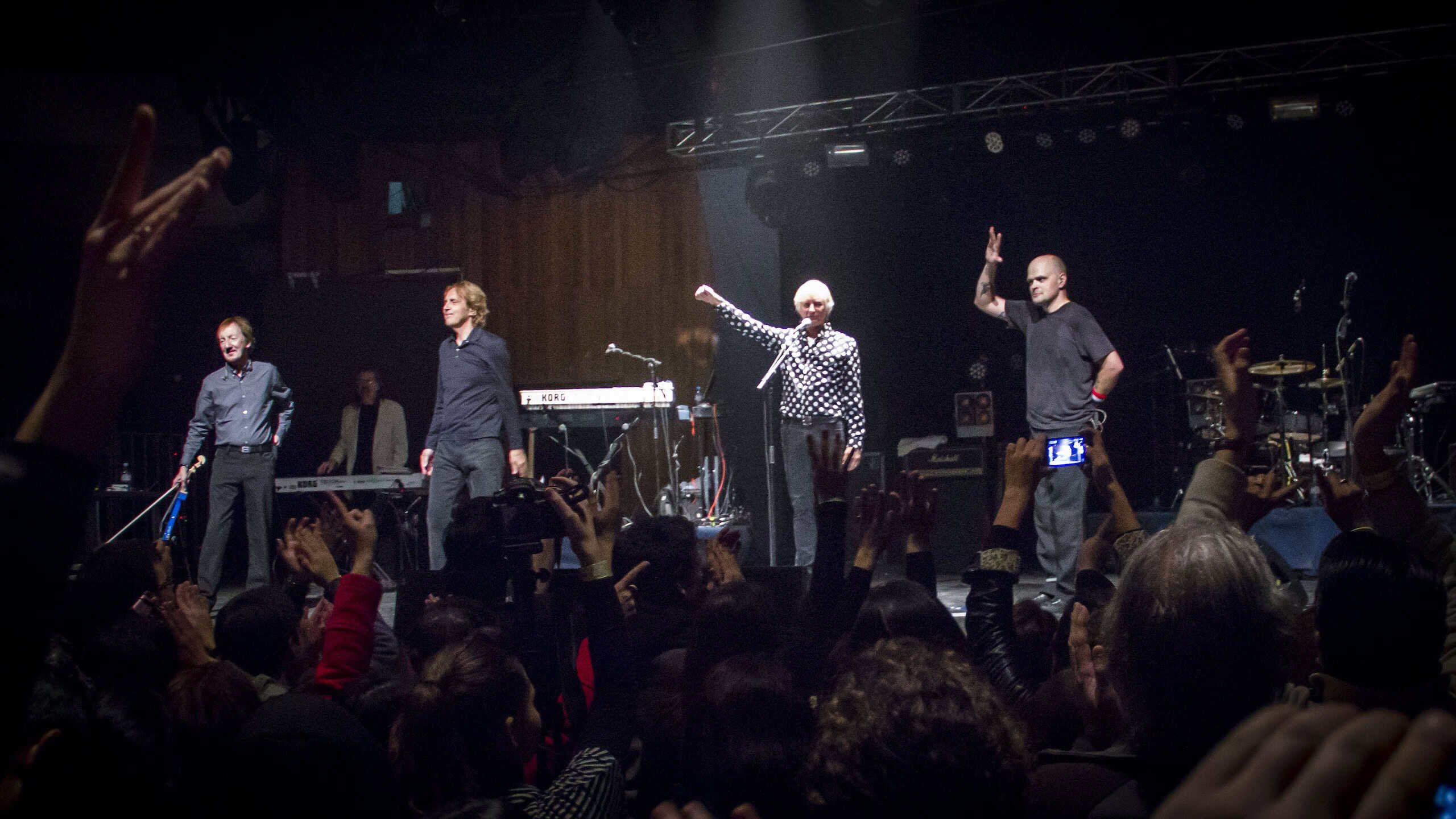 Ash & Pri band performing live on stage with audience.