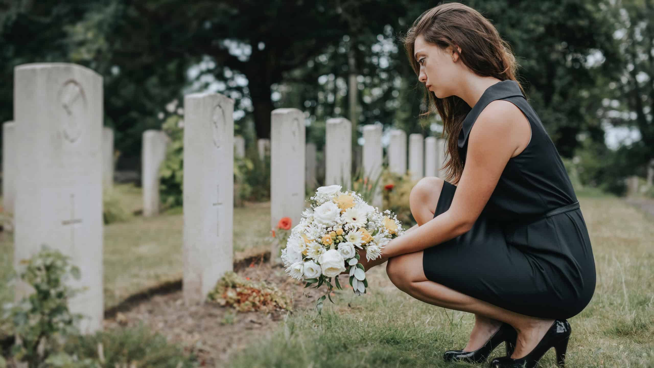 Young widow laying flowers at the grave
