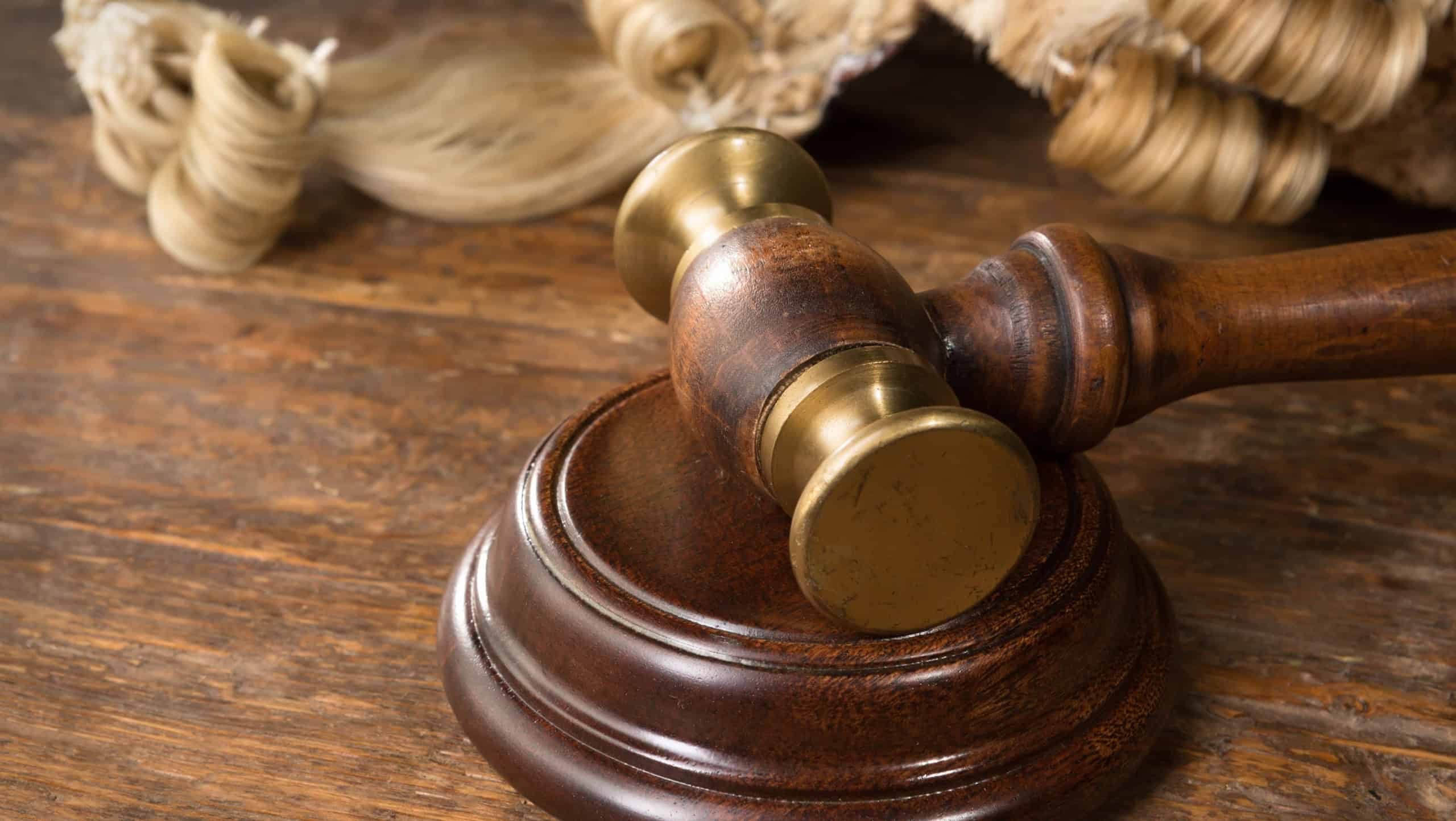 Wooden block, judge's wig and gavel on a wooden desk