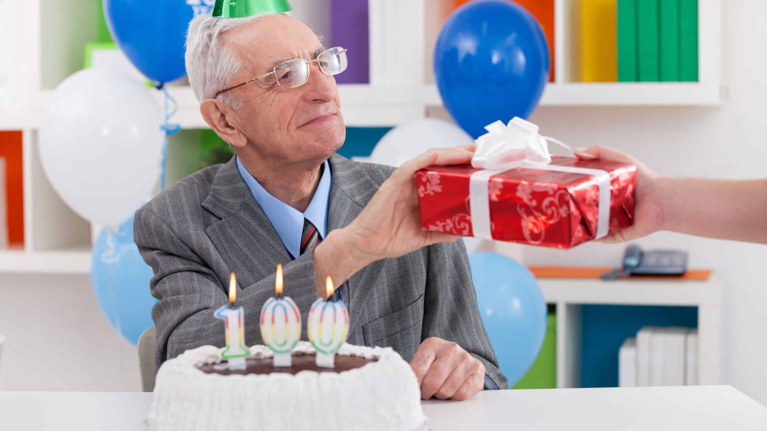 Senior man celebrating 100th birthday and receiving gift