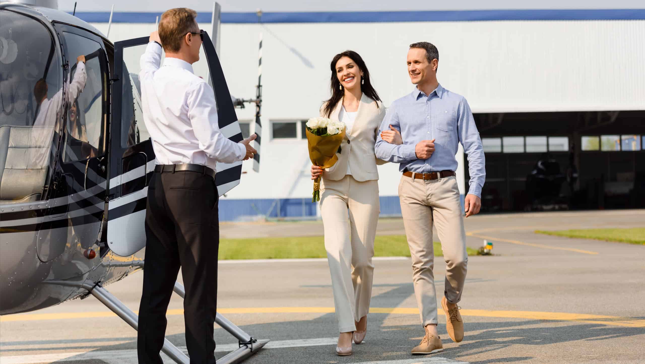 happy husband and wife on romantic date near helicopter and pilot