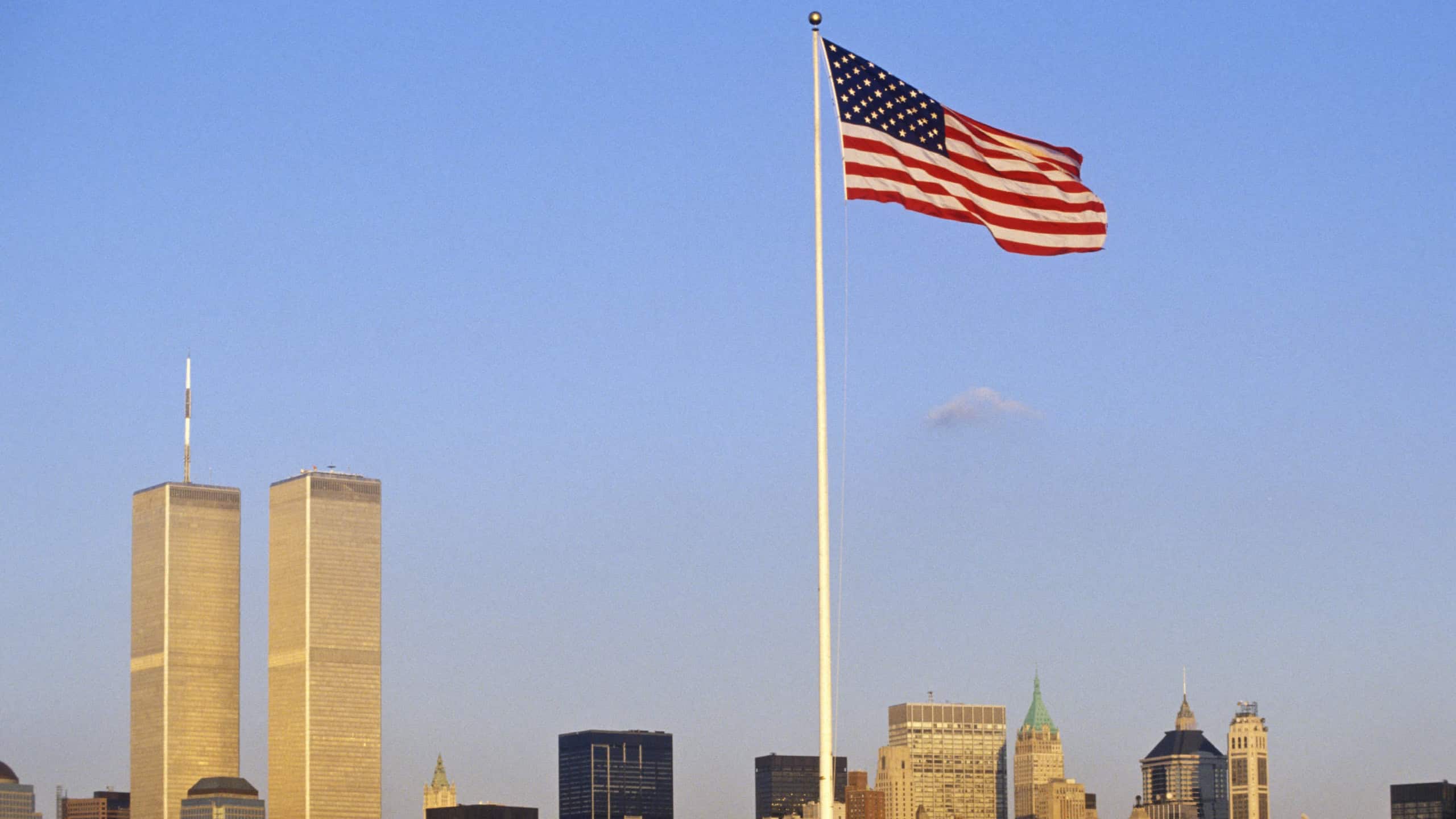 US Flag flying over skyline of New York City from New York Harbor, NY