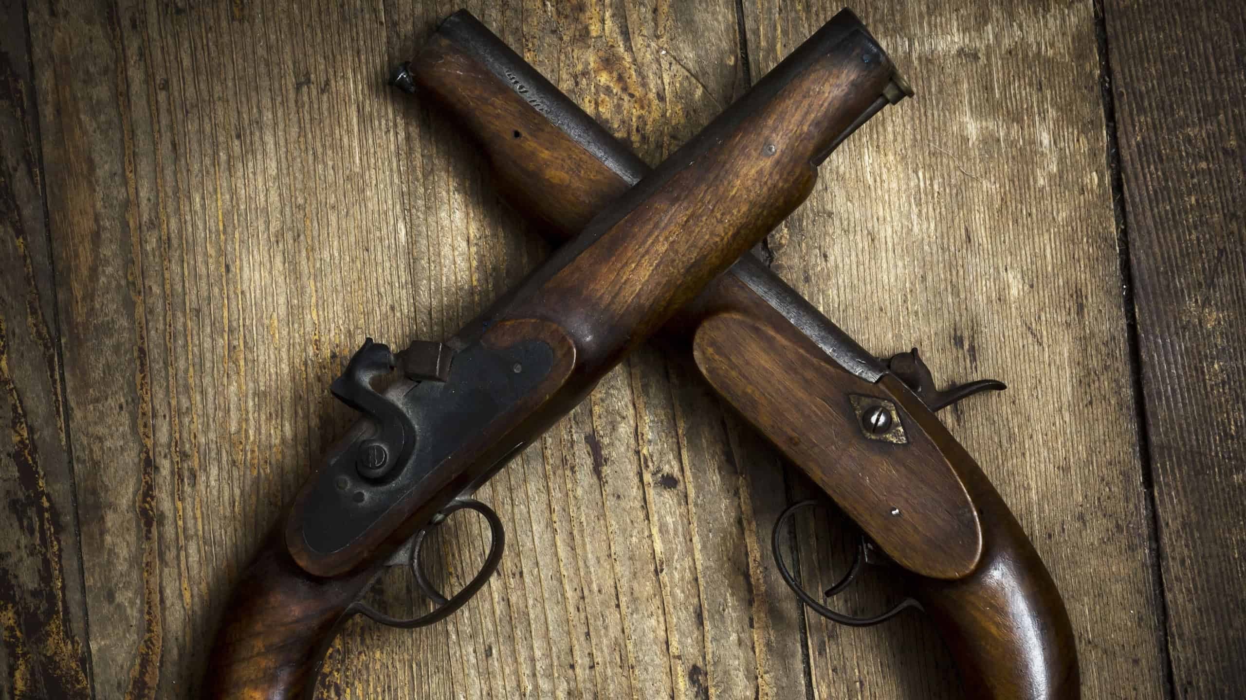 Two vintage pistols on wooden background