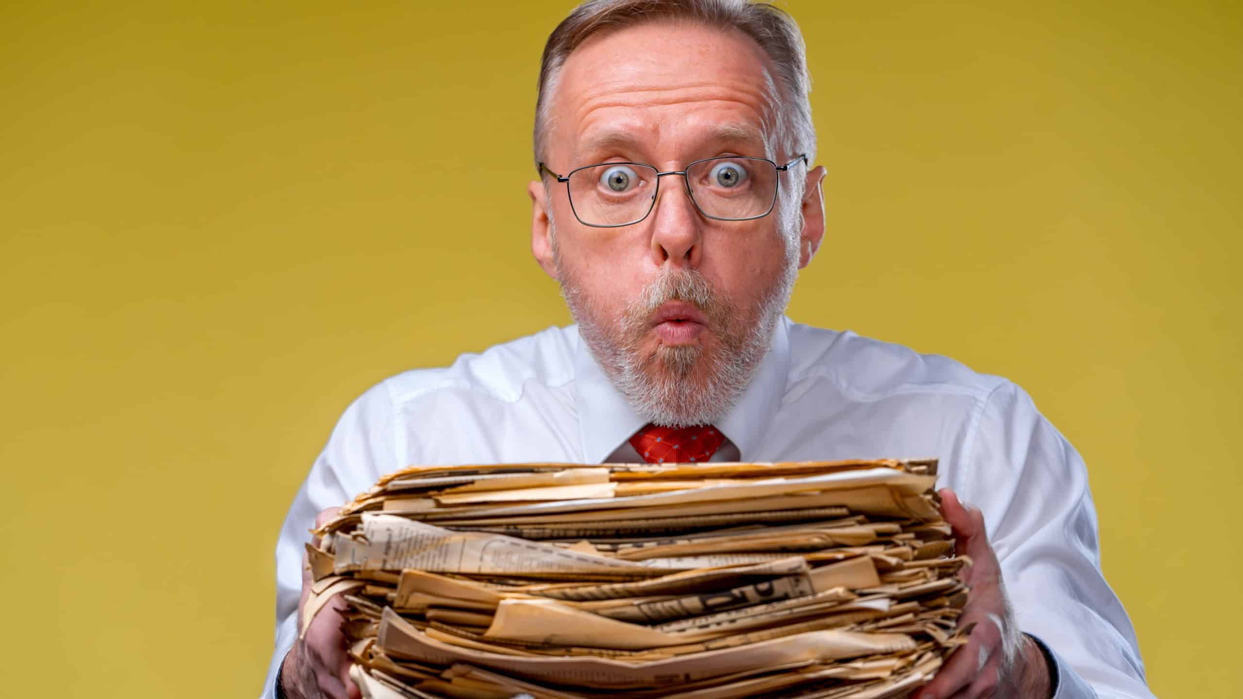 Pile of documents in hands. Senior man holdind piles of documents paper work. Surprised of hard mental work