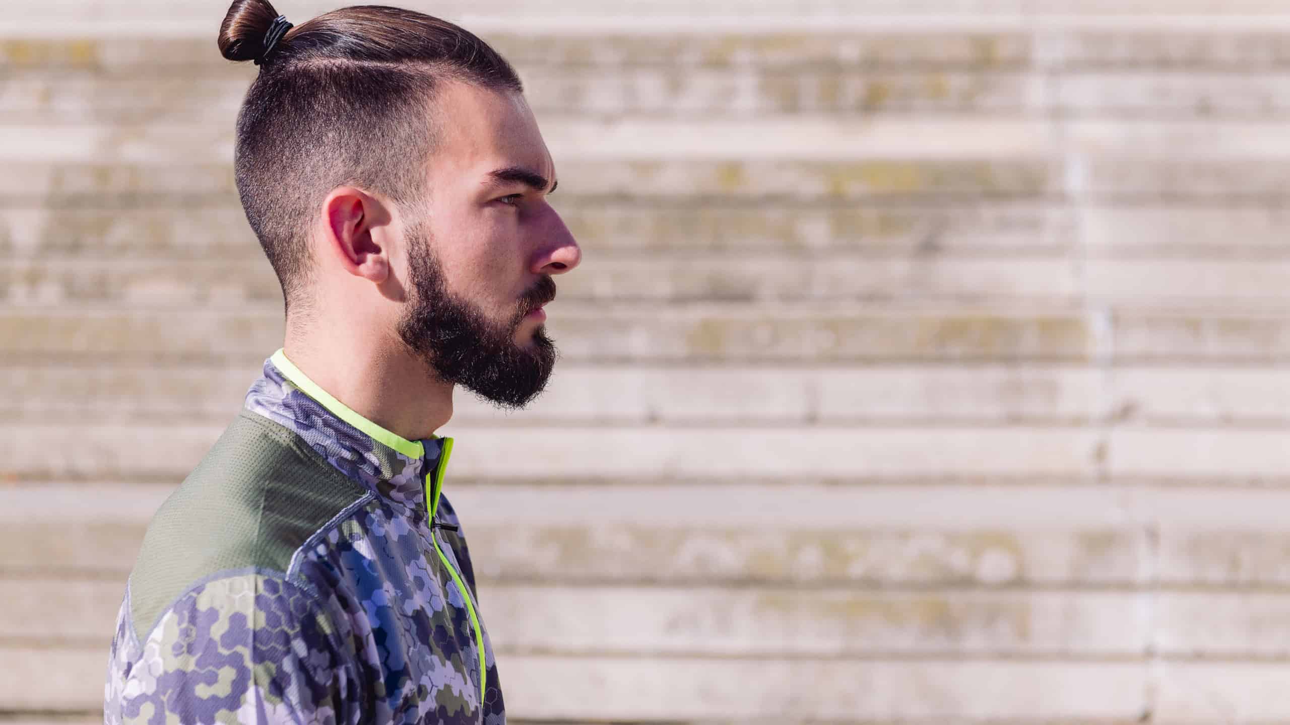horizontal portrait of a handsome sportsman with hair in a bun in a concrete background, concept of healthy lifestyle and urban sport in the city