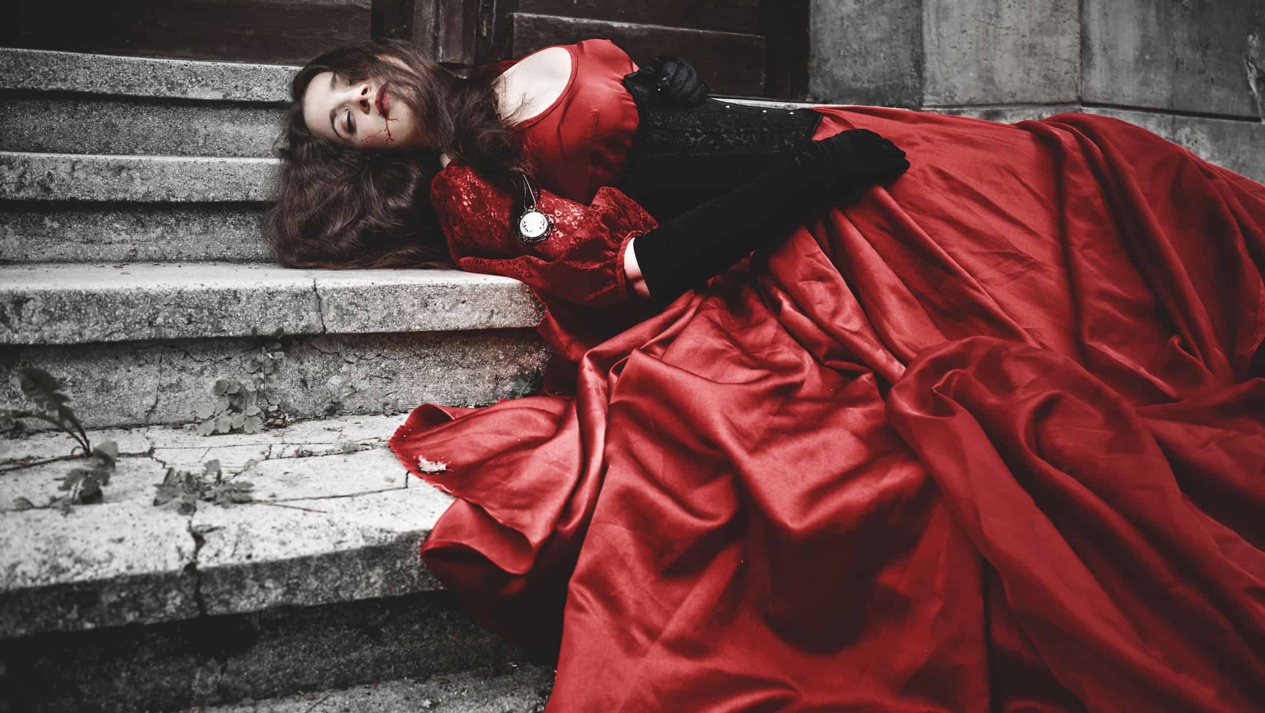 Lying and bleeding woman in a red Victorian dress