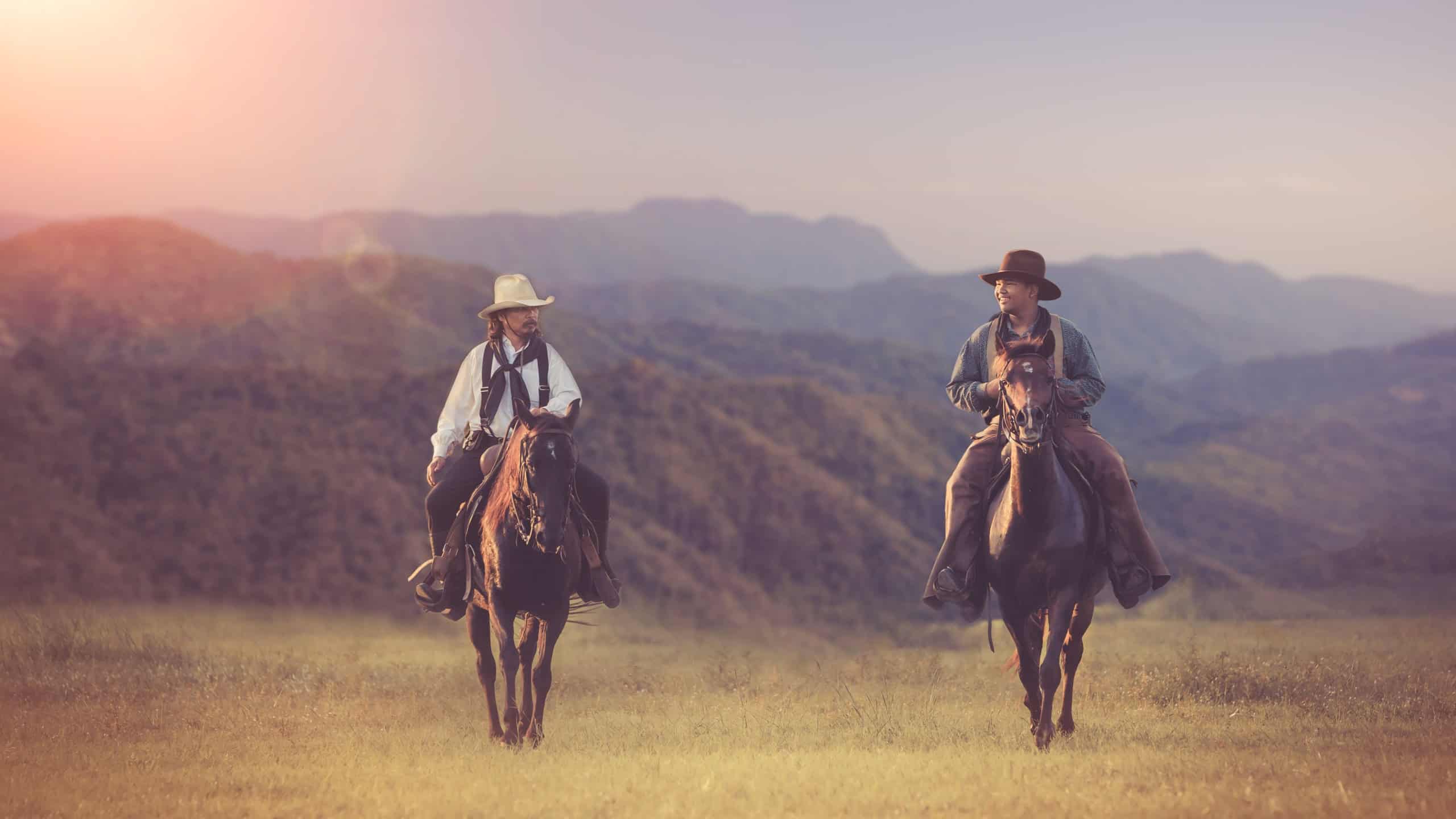 cowboys horseback riding at sunset time with sunlight ray sky nature mountain background.