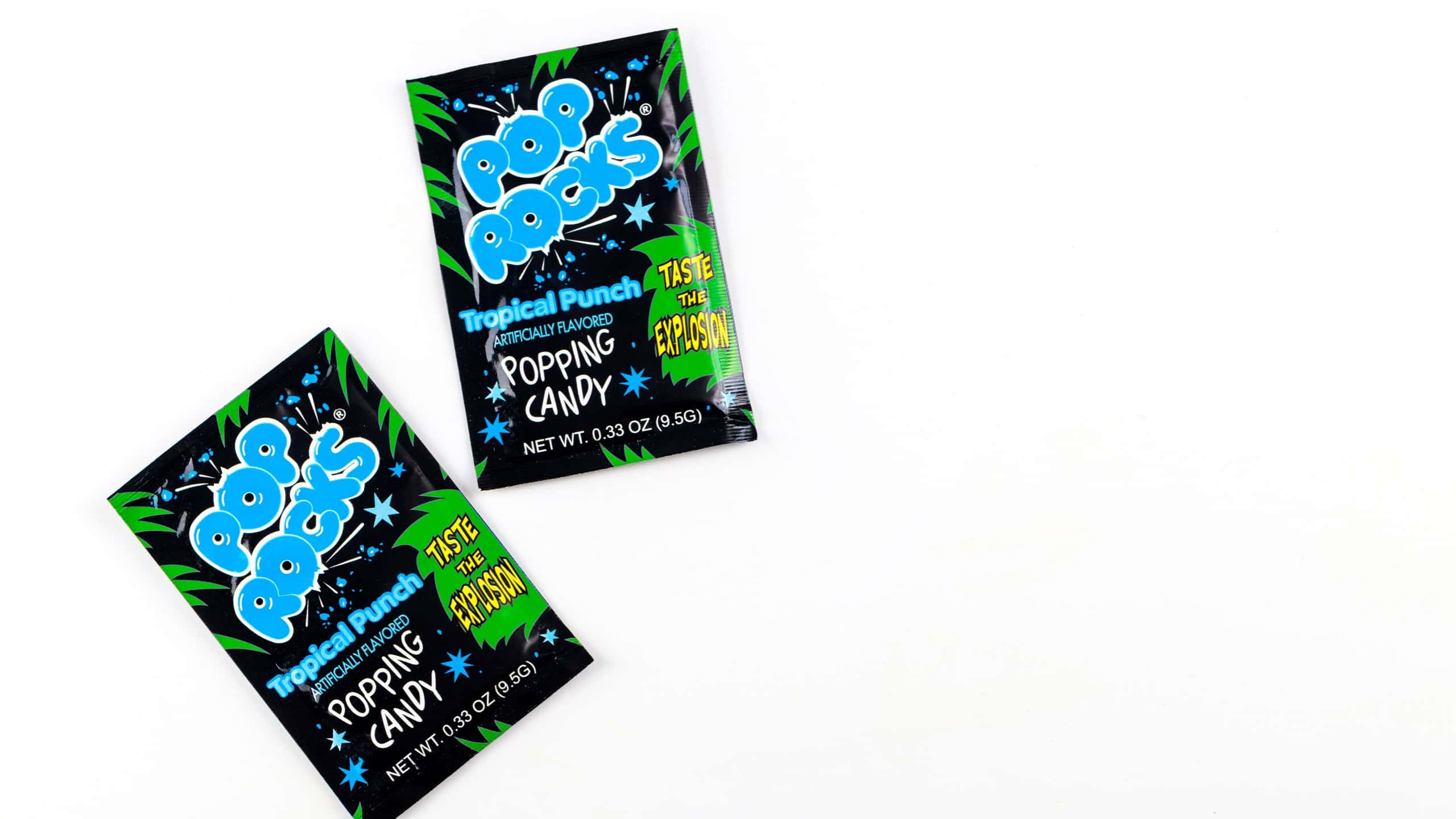 Two packages of Pop Rocks tropical punch candy on white background.