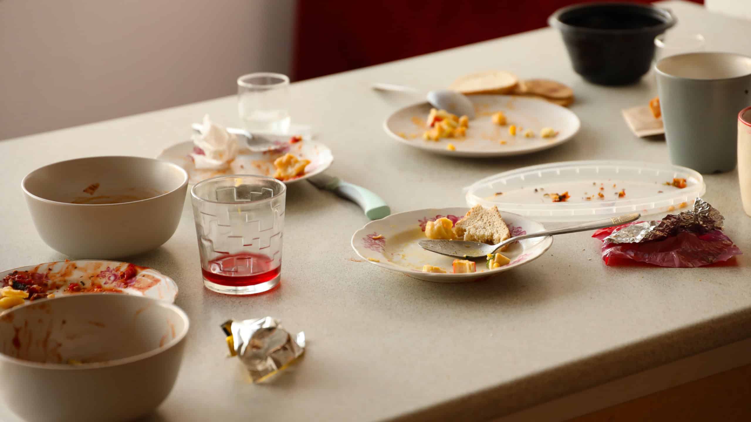 Empty dirty plates with spoons and forks on the table after meal. Banquet ending concept. Unwashed dishes ready to cleaning