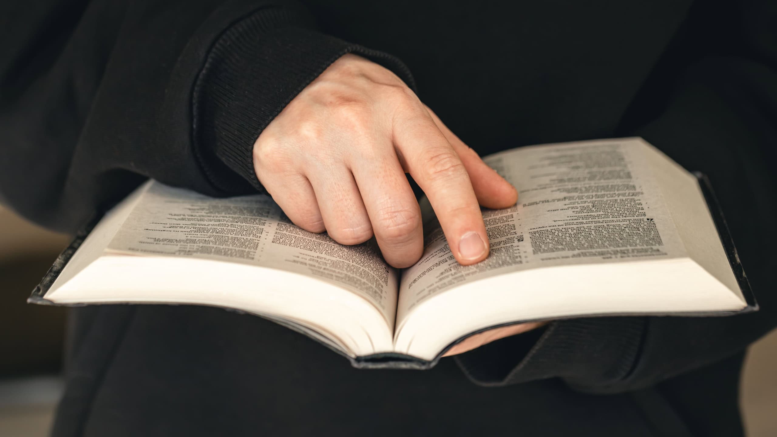 Open book Bible in male hands, close-up.