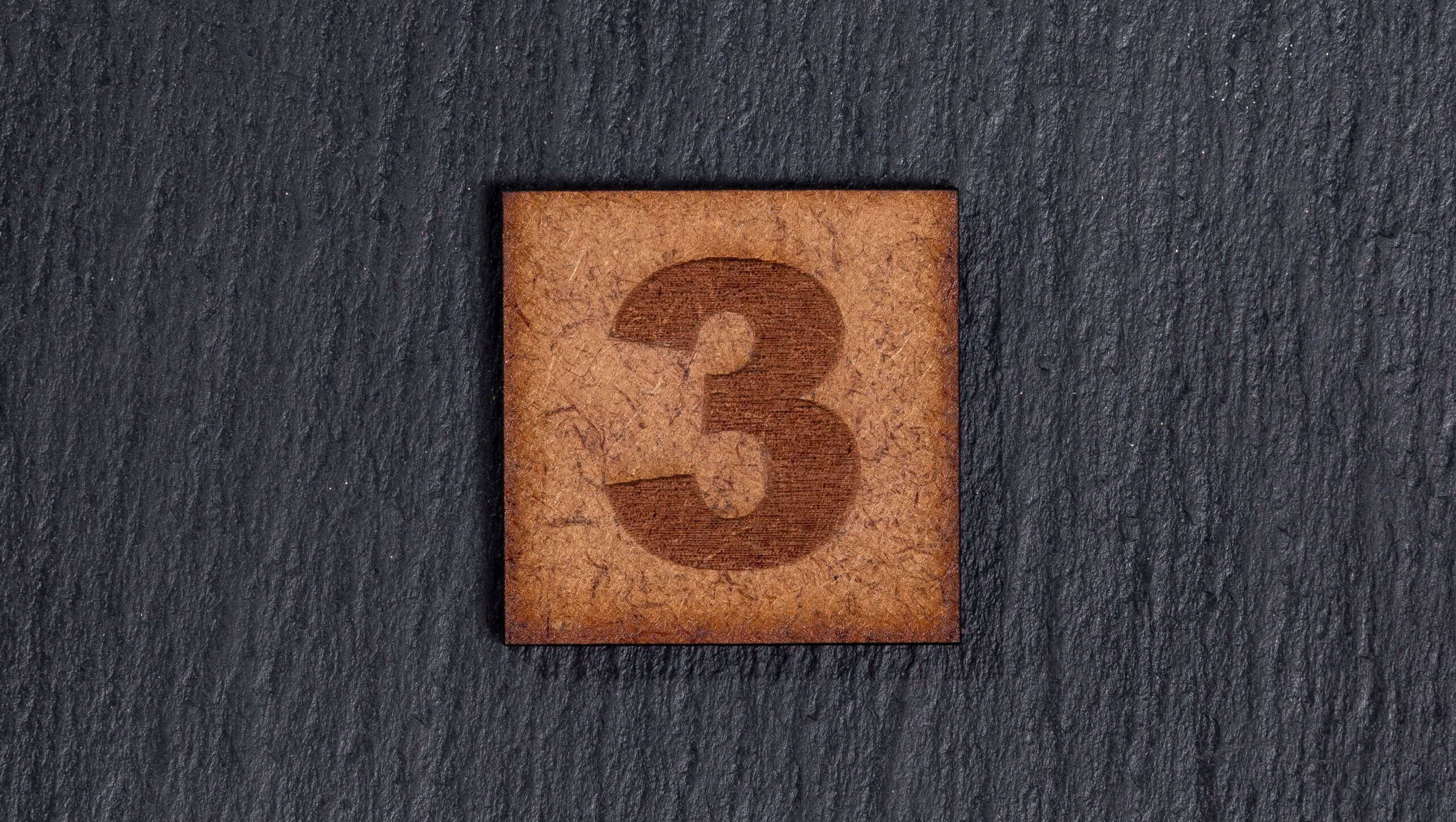 Number In Square Wooden Tiles - Number 3, On Black Stone Background.