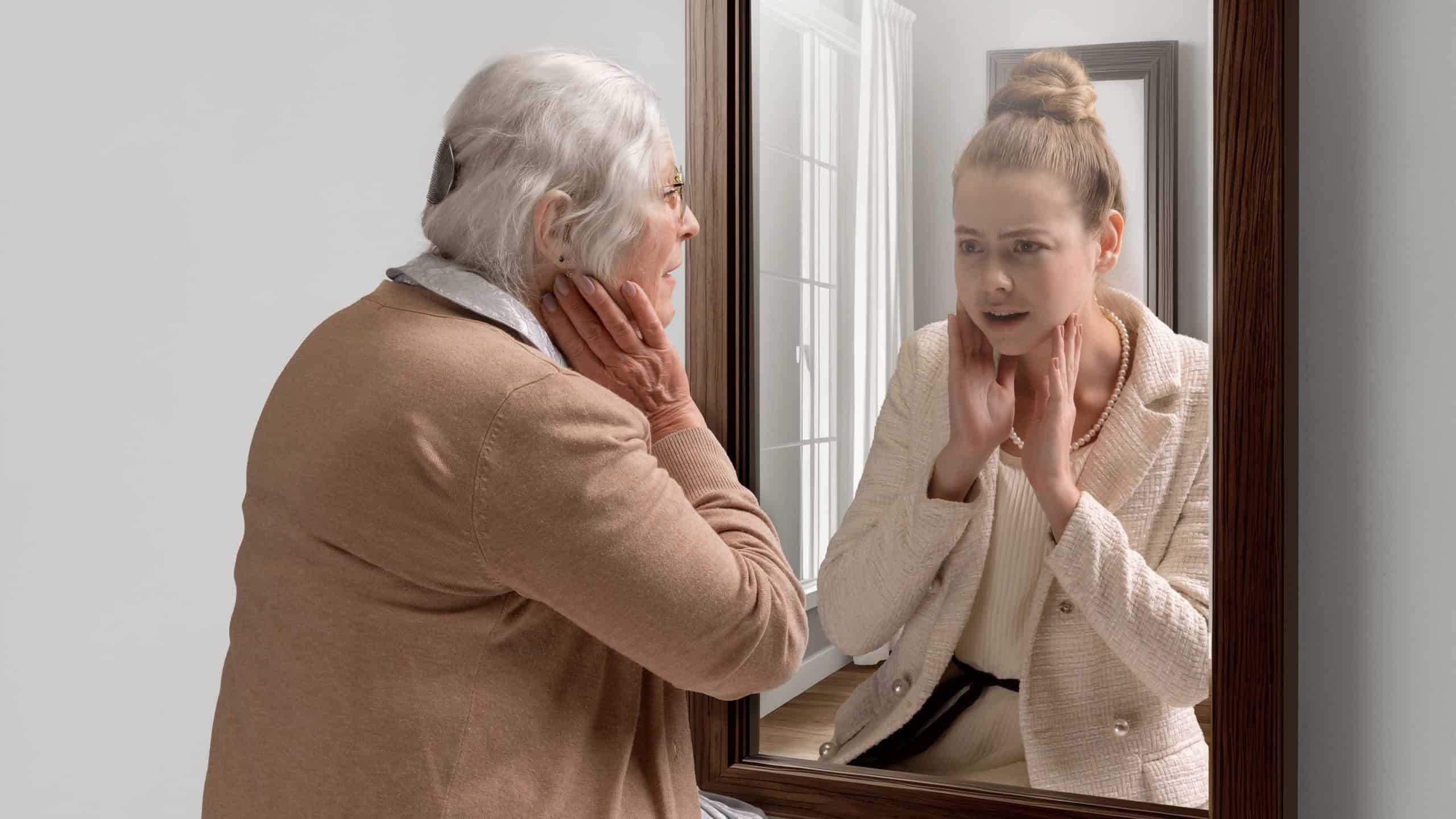Creative conceptual college. Senior woman looking in mirror with reflection of her young self. Aging process. Concept of present, past and future, age, lifestyle, memories, generation, ad